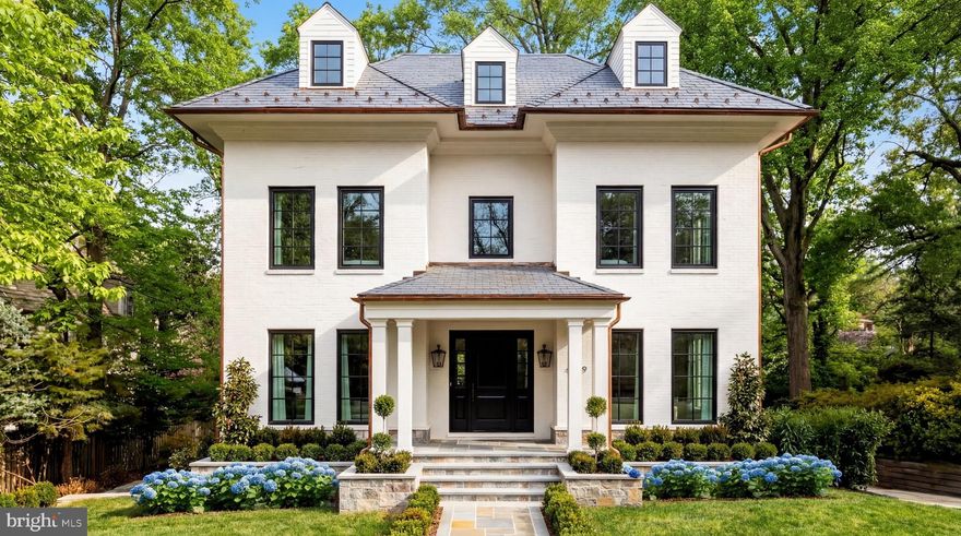 A grand architectural statement in the heart of Spring Valley, 4939 Quebec Street NW is a newly constructed masterpiece by Akseizer Residential, envisioned by Akseizer Design Group as a study in timeless craftsmanship and modern elegance. Executed from the ground up, the residence embodies a rare union of classical detail, transitional design, and advanced systems.

Perfectly sited on a deep lot along one of the neighborhood’s most distinguished streets, the exterior presents a quietly commanding presence defined by custom-profiled solid mahogany doors, Quaker windows, and disciplined architectural symmetry. A central flagstone path provides a gracious introduction.

Inside, wide-plank rift- and quartersawn white oak floors extend throughout, paired with a custom molding package including substantial baseboards, layered crown, and refined door casings. Custom paneled stairway walls and seven-foot solid-core doors finished in lacquer and paired with polished nickel Baldwin hardware create a cohesive aesthetic.

Formal living and dining rooms flank the reception foyer in a traditional center hall configuration, complemented by a richly appointed study featuring black lacquered pocket doors and a gas fireplace set in Pietra Grey marble.

The main living areas are anchored by a kitchen and family room where form and function coexist seamlessly. Custom cabinetry with solid white oak drawers is complemented by White Calacatta stone surfaces, including an integrated sink and waterfall island. Appliances by Wolf, Sub-Zero, and Cove are joined by Urban Electric pendants, Waterworks fixtures, and solid brass hardware. A fully equipped scullery connects to the formal dining room.

The adjoining family room centers around a gas fireplace framed in Calacatta marble with a white oak mantel and integrated television. French doors open to a screened-in porch, extending the living area outdoors.

Privately situated at the rear of the upper level, the primary suite features vaulted ceilings and bespoke millwork. The dressing room offers custom white oak cabinetry, fluted detailing, illuminated storage, a concealed laundry station, and a vanity with Calacatta stone top.

Clad in Calacatta Gold marble, the primary bath offers heated floors, dual vanities, a freestanding Waterworks soaking tub, and polished nickel fixtures.

Three secondary bedrooms share two appointed baths featuring marble tile and Waterworks fixtures. An expansive top-level loft introduces an additional bedroom and full bath.

The fully above-grade lower level features a lounge with wet bar and a flexible second living space. A separate area is ideal as a gym or private bedroom with en-suite bath. The level walks out to a private rear lawn via a covered loggia with an outdoor fireplace. A feasible rear yard expansion and pool installation is shown in our virtual tour, adding additional space and amenity flexibility. 

Engineered for comfort and discretion, the home includes sound attenuation, spray foam insulation, Lutron RA3 lighting control, distributed Sonos audio, full-home networking, security cameras, wireless HVAC control, and a private elevator. The garage includes custom wood doors and EV pre-wiring.

Executed with extraordinary attention to detail and reverence for enduring design, 4939 Quebec Street NW is a definitive Spring Valley residence exemplifying comfort and timeless elegance.