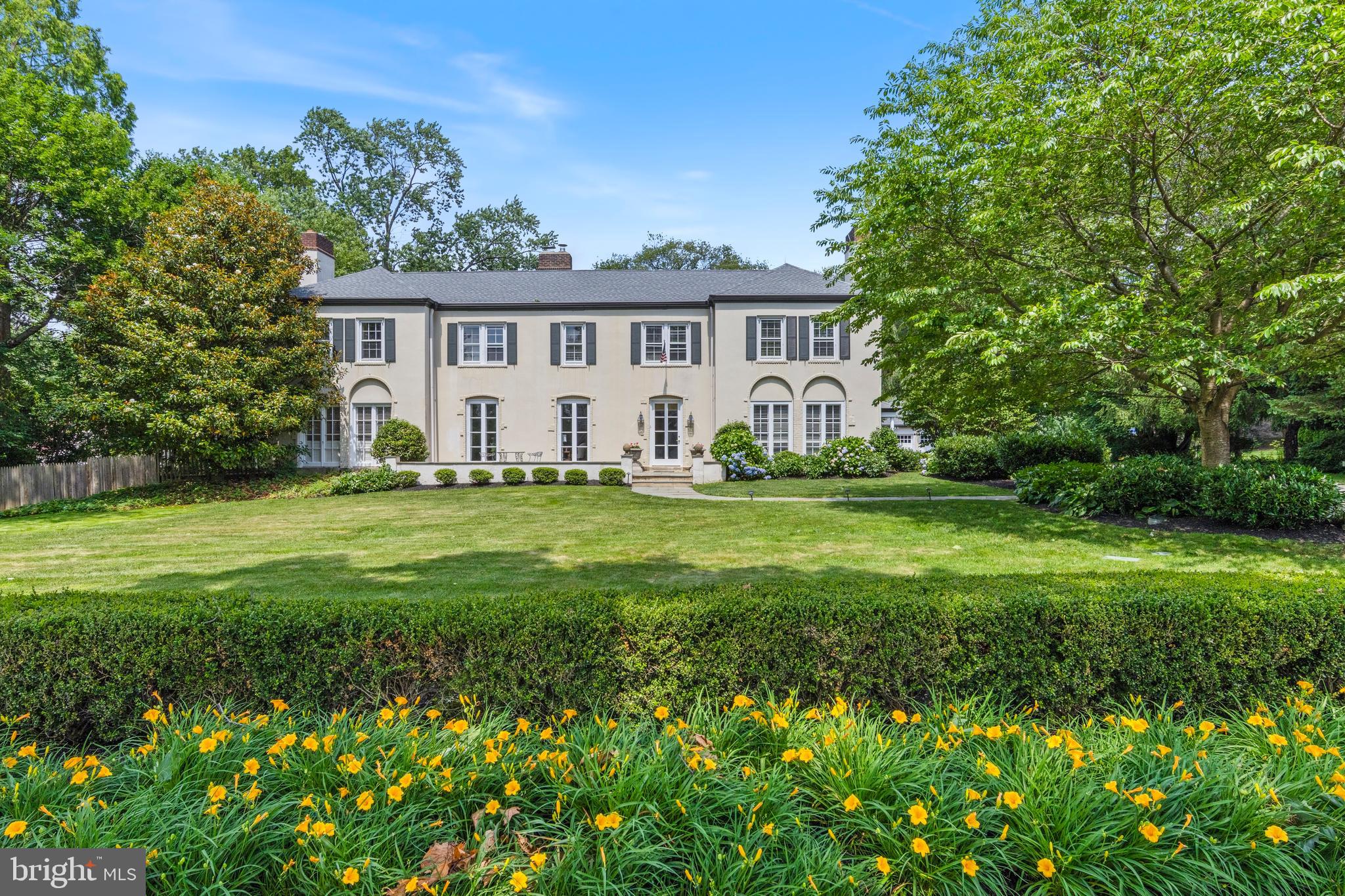 Located in one of Villanova’s most desirable and walkable neighborhoods, 103 Ashwood Road captivates w/ its classic symmetry, mature landscaping, and sweeping front lawn bordered by lush hedges and blooming gardens. A curved bluestone walkway leads to the gracious front terrace, flanked by multiple sets of French doors that enhance the home’s timeless architecture. Thoughtfully expanded and updated, this iconic Main Line residence offers modern comfort and privacy across two parcels totaling over 2 acres—1.5 acres with the home, pool, and detached garage, plus a nearly one-acre vacant lot.
With over 5,200 square feet of inviting living space, this 6 bedroom, 4 full, 2 half bath home is designed for comfort and connection. This fabulous layout opens to flagstone terraces connecting indoors and out. Whether hosting or enjoying daily routines, the home’s flow embraces garden views, light, and elegant, livable spaces ideal for both gatherings and quiet moments.
A front stone terrace creates indoor-outdoor flow across the living room, foyer and dining room. French doors line the façade, flooding the home with light. A striking glass front door opens to a vestibule and center hall anchored by a sweeping circular staircase with concrete treads, iron railing, and a rear-facing window. A powder room is located here. The sun-filled living room features the 1st of 3 fireplaces and opens to a cozy den w/ slate flooring, a 2nd gas fireplace, and French doors to a covered side porch. It also connects to a spacious family room addition w/ a custom-designed bar featuring cabinetry, quartz counters, and beverage refrigeration. Beyond the bar, a seating area is framed by a vaulted ceiling, windows, and French doors leading to the rear terrace—an inviting space that has hosted multi-generational gatherings and celebrations, but is just as cozy for quiet nights at home. To the right of the center hall, the formal dining room features a wood-burning fireplace, plantation shutters, grass cloth wallpaper and detailed millwork. A butler’s pantry w/ wood countertop, copper sink, glass cabinetry and wine fridge connects to the large kitchen—an inviting space w/ multiple windows and glass doors overlooking the gardens, pool, and home’s rear courtyard. Features include crown molding, white Country Kraft inset cabinetry, a cherry island refrigerator drawers and granite top, Subzero fridge, Bosch dishwasher, Thermidor double ovens, and a six-burner range. A wide cased opening leads to the breakfast room addition, where a triple window and triple French doors frame beautiful garden views. Custom built-ins w/ a desk offer a quiet spot for work. A charming mudroom w/ brick flooring, built-ins, and closets provides access to the driveway and detached 3-car garage.
Upstairs, new carpeting in all bedrooms. The hardwood landing leads to a private primary suite w/ a vestibule entry, two walk-in closets, and a spacious en-suite bath with large vanity, soaking tub, shower. Bedrooms 2 and 3 share a Jack-and-Jill bath; Bedroom 4 has its own bath and walk-in closet. Bedrooms 5 and 6, near the back staircase, are ideal for use as offices or flex space. A full bath #4, hall closet and laundry room w/ cabinetry complete the upper level. Outside, a striking pool is surrounded by multiple terraces, a pergola, and a large, private rear yard. The detached 3-car garage includes a pool changing room/storage and separate half bath, creating a private, beautifully designed setting.
Located in the enclave of Ashwood Manor, this walkable Villanova neighborhood is known for its timeless homes and vibrant community spirit. Steps from Villanova University’s campus, just .4 miles to the R5 train, .2 miles to Villanova Center, and close to the Radnor Trail, Bryn Mawr, Wayne, Devon and I-476 for easy commuting. Located in the top-ranked Radnor School District, with close proximity to many private schools as well as local country clubs. Agent is related to seller.