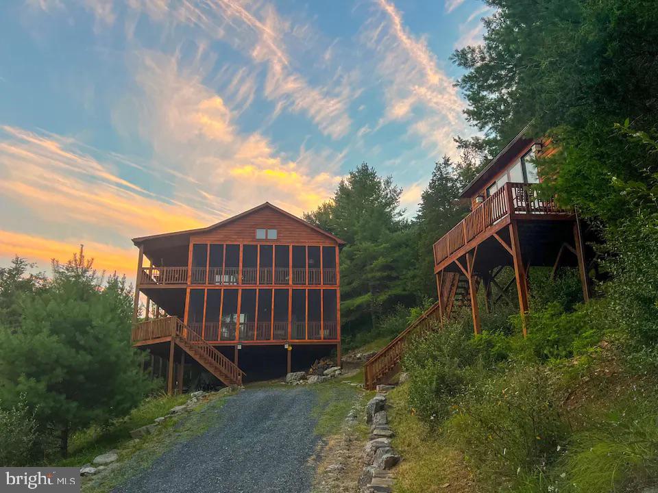 Discover tranquility in the heart of the coveted Lost River Valley with this stunning home offering the most breathtaking views in the area. Meticulously maintained, the exterior has recently undergone a complete staining, and a whole-house generator has been thoughtfully added, ensuring year-round comfort. There is High Speed Fiber Optic internet already installed for the convenience of working remotely. This 3-bedroom, 2.5-bathroom residence is a testament to both elegance and practicality. Ascend to the top floor, where a spacious dining area with hardwood flooring sets the stage. Matching granite countertops in kitchen and bathrooms. Revel in the warmth of a large wood-burning fireplace, not only indoors but also on the scenic screened-in deck—ideal for year-round enjoyment. The great room features a convenient half bath, bench seating for extra storage, and lofty ceilings that amplify the sense of space. The main floor hosts three bedrooms, including the primary bedroom with a large walk-in closet, hardwood floors, and slate tile in the bathrooms. The rustic charm of copper-punched sinks adds a distinctive touch. Both the primary bedroom and the second bedroom open to a generously sized screened-in deck, inviting you to connect with nature. Noteworthy are the successful Airbnb rental earnings for 2022 and 2023, available upon request. Tucked away for privacy, the property features a detached elevated yoga room(19X15)—a sanctuary to enjoy West Virginia's mountain views, providing a serene escape from the hustle and bustle of city life. This home offers more than just living; it's an experience—an escape into natural beauty, comfort, and the allure of the Lost River Valley. Don't miss the chance to make this hidden gem your own.