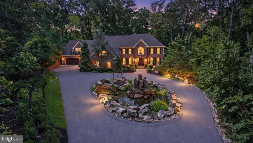 Welcome to Hidden Hollow: An extraordinary custom-built gated estate on over three acres with a separate guest house. This refined residence offers over 7,000 square feet of sophisticated living on a beautiful, private wooded lot at the end of a premier cul-de-sac. Conveniently located adjacent to Four Corners in Jacksonville and only minutes to Hunt Valley, it perfectly balances seclusion with everyday convenience.
Ideal for multigenerational living, the 5,500+ square foot main house boasts 4 bedrooms, 4 full and 2 half baths, delivering spacious, flexible accommodations for the primary household. Complementing this is a completely independent 1 bedroom, 1 full bath 1,259 sq ft guest house with separate entry, providing privacy and comfort for extended family or guests. 
A custom art-inspired water feature with basalt columns and propane torches welcomes guests at the circular drive, while two garages hold five cars for ease and convenience. Enter through the grand two-story foyer with overlook, flanked by a dining room and study, flowing into the expansive family room anchored by a floor-to-ceiling dual-sided masonry fireplace and a wall of windows. 
Dual chef-caliber kitchens delight: the main gourmet space with Fieldstone cherry cabinetry, granite counters, and premium appliances pairs seamlessly with a separate professional-grade chef’s kitchen featuring a Wolf commercial six-burner range with double ovens, True refrigeration, Bosch dishwasher, center island, ice maker, stainless surround, and two walk-in pantries. Additionally found on the main level is an office or potential bedroom, as well as a full and a half bath.
The upper level features a luxurious primary suite with soaring vaulted ceilings, a serene private sitting area, and an expansive custom walk-in closet designed for exceptional functionality and style. Its spa-inspired bath includes radiant-heated floors, raised tub, seamless glass shower, vessel sinks, heated towel racks, and water closet. The upper level also features three additional generously sized bedrooms, each boasting beautiful hardwood flooring, ample closet space with built-in shelves, plantation shutters, and a well-appointed full bathroom.
The lower level offers a true resort-inspired retreat, featuring a dedicated fitness area with a private sauna, a full bath, and a laundry room equipped with two full sets of washers and dryers, providing exceptional functionality for busy households. An expansive family/game room is elevated by a convenient wet bar and an adjacent wine cellar, perfect for entertaining. Ample additional storage includes a generous walk-in California closet that could easily serve as an additional bedroom. This walk-out lower level opens directly to a covered bluestone patio, seamlessly blending indoor comfort with outdoor living. 
Outdoor living shines with a maintenance-free 53-ft rear deck featuring built-in Basalt bar, a covered sitting or dining area with heaters, sliding doors and curtains, and recessed lighting; two raised seating areas, three fire fountains, overlooking terraced rock gardens and a fire pit. 
The home boasts an exceptional array of top-tier mechanical systems: an architectural shingle roof (2018) featuring 5-inch gutters and downspouts, a comprehensive water treatment system, multiple, updated HVAC units serving the home (replaced in 2025 & 2017), with dedicated zones. Additional highlights include a generator, new hot water heater for the main house (2021), a full Sonos whole-home audio system (covering the main house, master suite, bath, and deck), electronic Hunter Douglas shades in key areas, and three 1,000-gallon owned propane tanks. These meticulously maintained, high-end systems ensure peace of mind and effortless luxury living.
This exquisite private retreat is more than a residence: it's a legacy of refined luxury, seamless entertaining, and lasting family harmony.