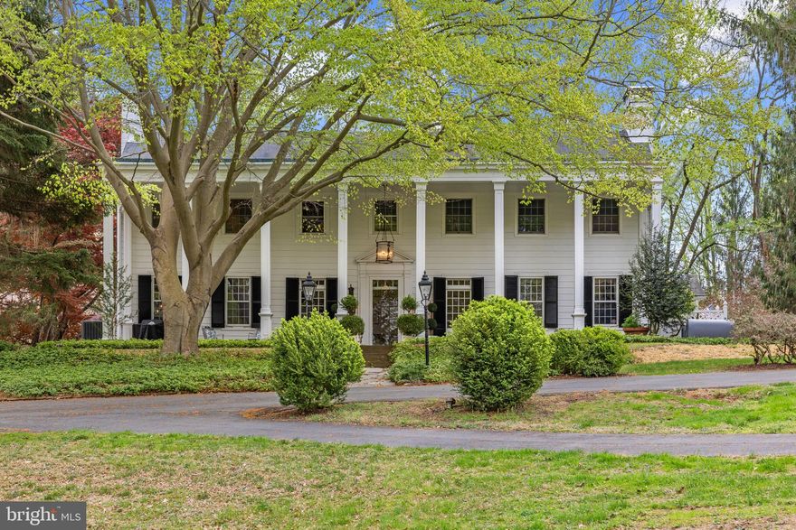 Tucked away on beautifully rolling and wooded grounds, this 1934-built Southern Colonial blends timeless charm with understated elegance.  Surrounded by mature specimen trees,  this home offers  exceptional privacy and serenity.  The grounds are remarkable, with expansive lawns, wooded areas, a tennis court, and access to walking trails at Gunpowder State Park.    Parking is plentiful with a newly constructed 3 car detached garage with overflow parking and a  circular driveway in front of the home.  
A classic two-story columned porch opens to a gracious foyer setting the tone for the rest of the home.  the main level boasts high ceilings, rich moldings, arched doorways, wide peg hardwood floors, and multiple fireplaces.   The grand living room is accented  with a fireplace with custom moldings and built ins and  large windows with beautiful view.   An oversized great room offers impressive scale, ideal for entertaining or movie nights and also has striking views.  The charming & tastefully  kitchen has and granite countertops as well as  new stainless steel appliances.  Adjacent to the kitchen is a quaint and light filled breakfast room with access to the side yard and garages.   A formal dining room is located just off the kitchen.  
At the heart of the main level is a spacious bar room—perfect for entertaining—with extensive cabinetry, countertops, a wet bar sink, and an ice maker. Off the kitchen is a generous mud room, which could easily be transformed into a charming, sun-filled breakfast room.
Two staircases lead to the second level, where a wide central hallway connects four bedrooms and three full bathrooms. The primary suite includes a generous bedroom,  beautifully renovated bath, and walk-in closet.   A rare opportunity to enjoy classic architecture, privacy, and flexibility in a truly special setting.
