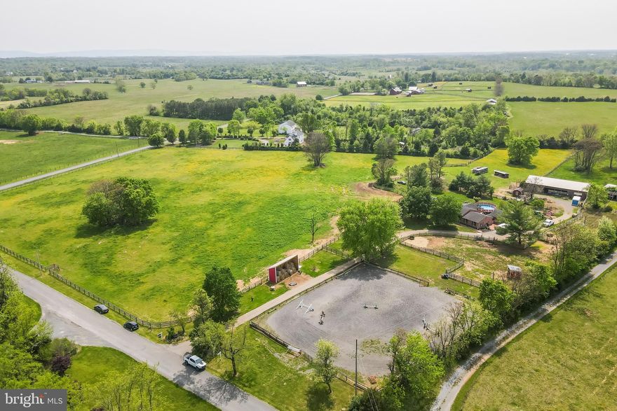 Amazing turnkey equestrian property, with endless possibilities, rarely seen at this price point in
beautiful Clarke County, Virginia. The horse amenities are a horseperson’s dream. Enjoy year-round riding in the 100x150 professionally installed sand/bluestone arena with French drains. Set up a full course of jumps to practice for horse shows. The six matted stalls (there is a seventh stall that is not matted) each have waterers with individual shutoffs. Each stall has 4 inches of bluestone to allow for proper drainage of liquid helping to keep your barn smelling fresh and clean. The wash stall and grooming stall are separate preventing clogging your drain with clippings. The wash stall also boasts a textured floor to prevent slippage when wet. All water lines in the barn are run with PEX pipe to prevent them bursting due to freezing temperatures. The barn office is enormous and has a personal tack room. The metal-lined and insulated feed room keeps unwanted critters out and the feed safe and mold-free for your horses. It also boasts built-in 800-pound capacity feed bins and an area to prepare the feed buckets while charging your phone at the USP charging outlet. Makes feeding a breeze.  The office also has a walkout to the smaller 2 stall barn and pony paddock. Adjacent to the office is a workshop accessed via the garage door- all separate from the office. The whole perimeter is protected with three-board fencing and a gate. All paddocks, including the four-board stallion paddocks are interconnected so you never have to worry about a horse escaping while moving them between paddocks. Adjacent paddocks are double-boarded. The four-board stallion paddocks can also be used for special needs horses. Additionally, you can raise chickens in the chicken coop capable of housing 20 plus chickens. For the humans, there are endless possibilities. Live in the 4-bedroom/4 bath home with a separate but attached small apartment and run an equestrian business yourself. Or live here and rent the horse facilities and apartment to a horse trainer, bring your horses, goats, cows – whatever, and offer boarding to others. Your imagination is your only limitation. The kitchen/family room with a gas fireplace is a dream to work in with custom cabinets with pullouts, granite countertops, and all Stainless Steel appliances.  This area opens onto the deck to make grilling easy and convenient or to keep an eye on the friends and family who are enjoying the attached above-ground pool. The kitchen opens to the current dining room allowing for a large or expanded dining table for Thanksgiving or other large gatherings. The space could also be a living room or expanded family room and has a wood-burning fireplace. The current huge living room is adjacent and could serve as a game room – think pool table, air hockey, whatever. The master suite is enormous (30x30) with vaulted ceilings and its own small deck overlooking the largest paddock where you can enjoy watching your horses graze. It includes a large walk-in closet as well as washer and dryer and newly tiled master bath with a secondary walk-in closet. Another bath and 2 bedrooms – one with a wood-burning fireplace complete the upper level. From the living room a short hall connects to the “in-law” suite with recently redone floors, SS appliances, and a remodeled bath and rustic farmhouse kitchen. The basement has its own outside access, storage space, another full bath, washer-dryer and completely redone room -that can be a “bedroom”, man-cave, office, living quarters for farm hand, rental space – again possibilities abound. Current owners started adding another kitchenette, finish it your way and you can have another complete apartment. Schedule a showing today!!!