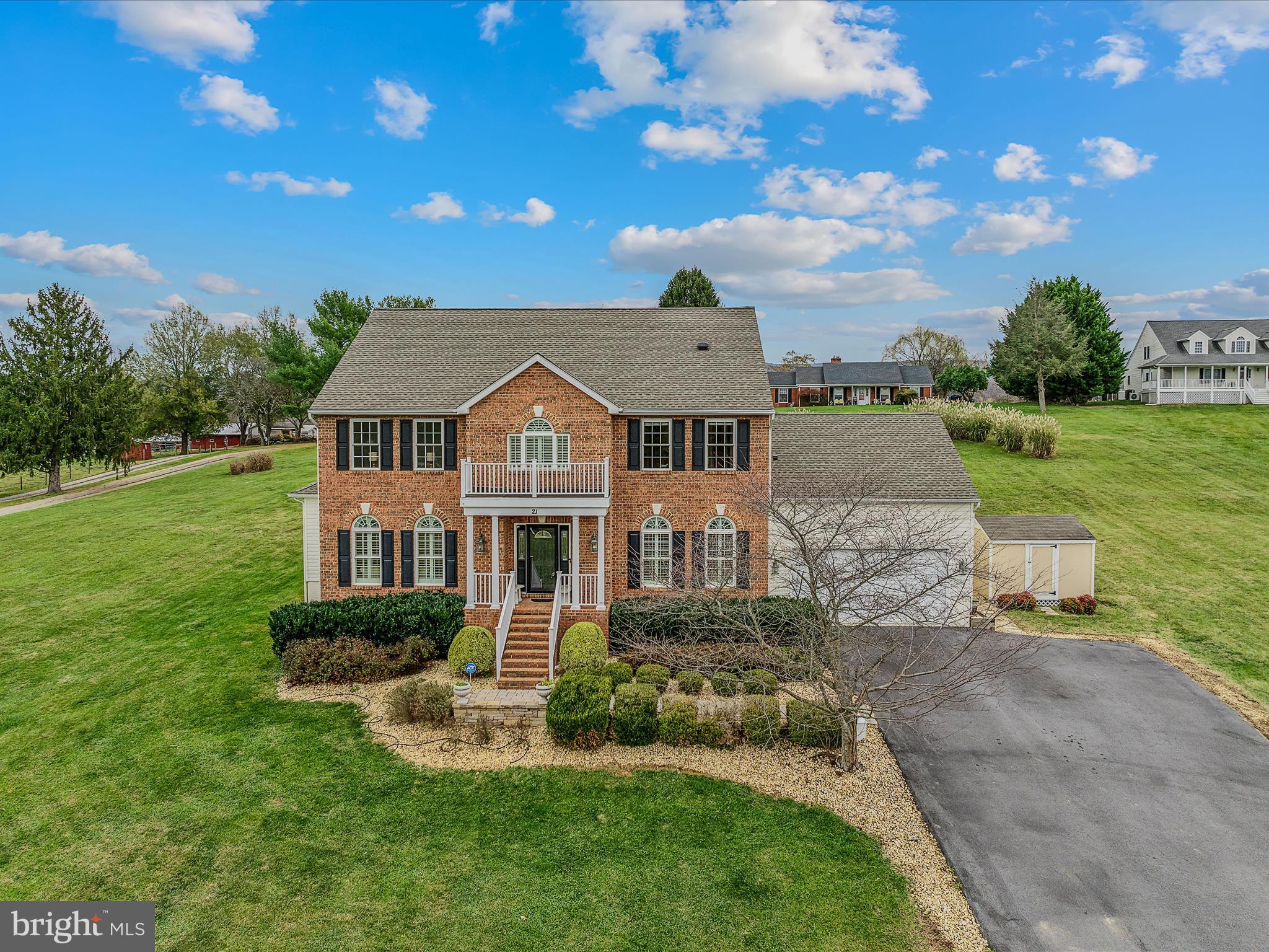 Step into this impressive, custom-built, two-story brick-front home. Nestled on a spacious 2-acre lot with minimal community restrictions, this six-bedroom home offers access to the Shenandoah River while combining rural tranquility with convenient commuter access, just a short drive from Northern Virginia. The main level opens with a grand entryway featuring a curved staircase and flows seamlessly into an inviting layout. The luxurious primary suite on this floor offers a modern flare with a custom panel wall design, quartz counters & tile flooring. The primary bath also features a soaking tub, a separate tiled shower, and a large walk-in closet—your perfect personal retreat. A private home office is adjacent to the primary suite, which is ideal for remote work or study. Much of the main level features hardwood flooring, which adds warmth and sophistication to the space while creating a seamless flow from room to room. The formal dining and living rooms offer additional gathering areas, and the family room serves as a cozy retreat with a gas fireplace and access to the rear deck and patio. At the heart of the home is a beautifully designed kitchen equipped with a gas cooktop, double oven, center island, and breakfast nook, providing both functionality and elegance. The upper level features two full bathrooms and five spacious bedrooms with large closets, providing ample space for sleep and play. This design prioritizes convenience and privacy, offering comfortable accommodations for family or guests. The partially finished basement provides versatility with a large recreational room and a multi-purpose room, making it ideal for a home gym, crafting, or homeschooling. A large portion of the basement is left unfinished, allowing for storage or future expansion. The outdoor spaces are perfect for relaxing or entertaining friends and family and have a fantastic view. The property also includes an oversized two-car garage, a large detached shed for additional storage, and an exterior dedicated electrical RV hookup. Experience the best of West Virginia living with lower property taxes, a slower pace of life, and more affordable real estate, all while remaining conveniently close to neighboring states.