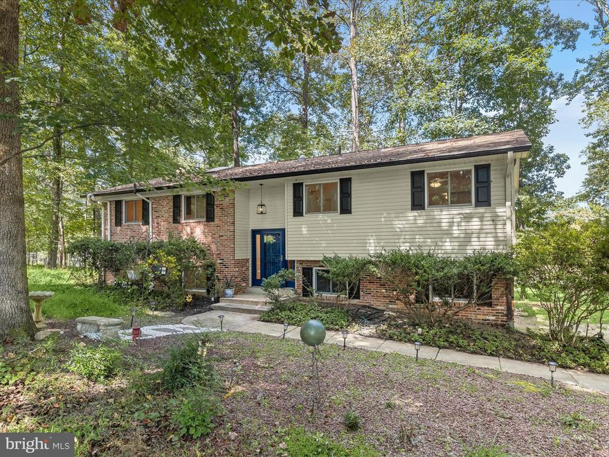 Set on a picturesque 0.92-acre corner lot in the sought-after Woodmark neighborhood of Ellicott City, this custom-built home combines timeless character with thoughtful updates. Offering four bedrooms and three full bathrooms, the residence is surrounded by mature trees that provide both privacy and a serene backdrop. Inside, recently refinished hardwood floors highlight the inviting living room, where crown molding adds elegance and seamlessly continues into the dining room accented with built-in cabinetry. An updated eat-in kitchen boasts stainless steel appliances, quartz countertops, a skylight that brings in abundant natural light, and space for a breakfast area. Just off the living room, a spacious screened porch with skylights creates an ideal retreat to enjoy views of the wooded surroundings. Hardwood floors extend down the hall to three comfortable bedrooms on the main level, including the primary bedroom with its own private bathroom featuring a walk-in shower. The second bathroom on this level has a tub shower. Downstairs, the fully finished lower level offers versatile living space with a fourth bedroom, a beautifully renovated bathroom with dual sink vanity and walk-in shower, and a cozy family room anchored by a brick-surround gas fireplace. Sliding glass doors open to the backyard and patio, creating a seamless flow between indoor and outdoor living. Practical features include a utility room, a two-car garage with laundry, generous driveway parking, and a shed for extra storage. Peace of mind comes with numerous updates completed in recent years, including new bathrooms, flooring, roof, windows, doors, HVAC system, water heater, water softener, and attic insulation. This well-maintained home provides comfort, space, and a connection to nature while remaining close to all that Ellicott City has to offer nearby. Some images have been virtually staged.