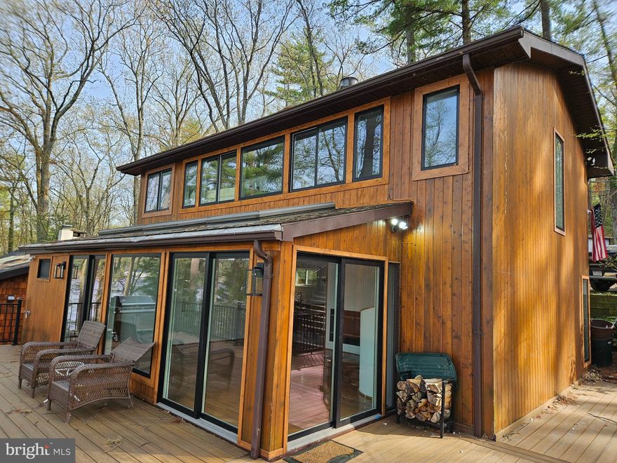 100' Lakefront Living on Lake Wallenpaupack at NO HOA Simons Point! Priced right based upon recent appraisal. Wake up to sparkling water views in this 4-bedroom, 3-bathroom (2 ensuite bedrooms) lakefront contemporary retreat boasting 1,300 square feet of thoughtfully designed living space. With your own private dock for up to 4 boats and jet skis just steps from the back door, enjoying boating, fishing, and lakeside lounging on 100' of lake frontage from your new elevated composite deck. The home was designed by the former owner and designer and features a unique layout. Inside you'll find a bright, airy layout enhanced by multiple skylights and lots of new, large windows and doors, that capture lots of light and great views. A cozy gas fireplace warms the main living area and the new hickory kitchen with all-new stylish appliances, make it perfect for hosting family and friends. The second-floor primary suite overlooking the lake offers lots of lake-view windows and an ensuite soaking tub. A co-joined Queen bedroom and Bunkbed room share an ensuite bath with tile shower. There's one Queen bedroom on the main floor and a full bath and laundry room to round out the convenience of lakefront living. Additional features include wood siding for rustic charm, a firepit for lakeside evenings, and a modern on-demand tankless water heater for efficiency. Owner had professional home inspection to rule out any problems and will be putting on a new roof in the coming weeks. Whether you're looking for a weekend getaway or a year-round residence, this property delivers the ultimate Lake Wallenpaupack lifestyle—relaxation, recreation, and unforgettable views. Owner is a PA licensed real estate professional. Property also includes the original garage and tool shed. Use your creative genius and turn this charming little building into a wonderful potting shed, tool shop or guest space.