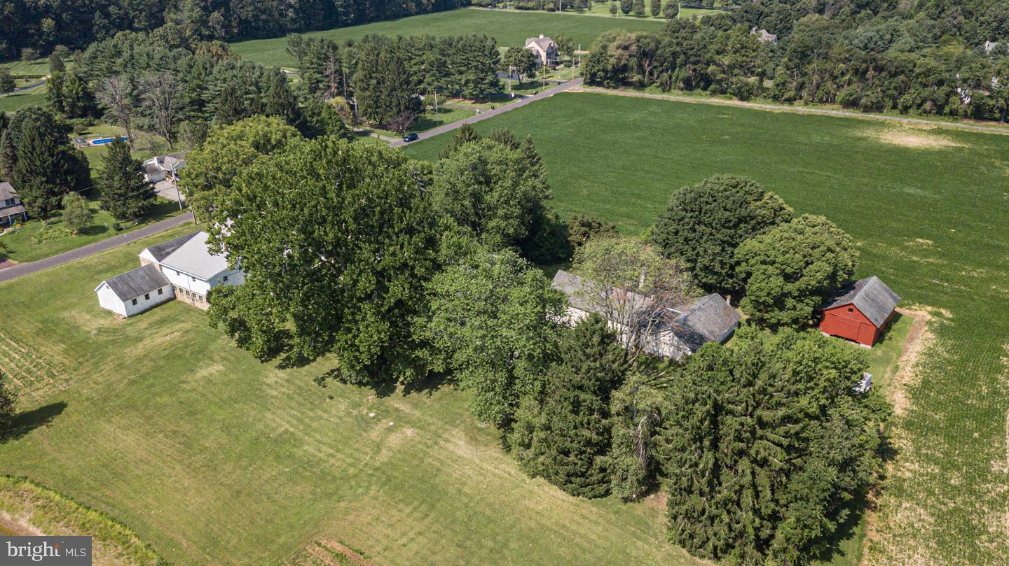 Welcome to Iron Apple Forge, the epitome of modern-day Bucks County farm living. Step up onto the porch and step back in time in this lovingly maintained Bucks County farmhouse. Situated far back off a quiet country road on nearly 12 acres surrounded by mature trees, a pond, and 3 barns is the farmhouse dating back to the 1700s. Showing pride of ownership, the original pine floors grace the living room and dining both complete with gorgeous stone fireplaces. Inviting details such as pocket doors, beehive oven, plaster walls, and custom made hardware can be found throughout the home and bring out the antique nature. The heart of the farmhouse, the kitchen, has all the modern conveniences while maintaining the character such as original hand blown window panes. Cherry cabinetry, granite countertops and stainless steel appliances adorn the room while rustic details like an exposed stone wall and large cooking fireplace remain.  A mudroom/coat room with plenty of built in cabinetry complete the first floor. Taking the beautiful hardwood staircase to the 2nd floor you are greeted by a sizable hallway with a sitting area. Pine floors grace the entire 2nd floor. The main bedroom is spacious and has an enormous walk-in closet with built-ins, additional closets and updated main bath. The washer and dryer are conveniently located on the 2nd floor. There is also a rear pie staircase in the main bedroom leading to the kitchen area for convenient access. Two additional bedrooms, both with fireplaces, share an updated hall bath with separate tub and shower. The charming property has so much to offer including low taxes with Act 319! The outbuildings include a separate 2 bedroom, 2 bath apartment, barn and large heated workshop. Offering plenty of peaceful open space to get away from it all but still close to dining and shopping. Central Bucks School District. A true retreat! Come experience it today.