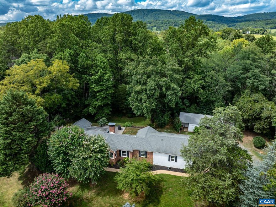 Step into this private, thoughtfully updated, one-level home and experience comfortable living on a spacious 2.48-acre lot in Keswick. As you enter, the open living room and dining, or sitting area, welcomes you with hardwood floors and a cozy gas fireplace, leading you to a bright, inviting sunroom. The main level features a split bedroom design with two bedrooms and an updated full bath down one hall. Across from the living room, you'll find the eat in, renovated kitchen, complete with subway tile backsplash and elegant quartz counters. Retreat to the primary suite, which includes two closets and an updated full bath with a custom vanity and tiled shower. The expansive rec room offers endless possibilities, perfect for a studio, in-law suite, or additional living space with plenty of room for storage and entertaining. Outside, the fenced backyard is your private oasis. Enjoy seasonal mountain views from the stamped concrete patio, or utilize the space for gardens, pets, and play. The home's location provides easy access to I-64 and Pantops. Recent upgrades include 17 new windows (2020), a new heat pump (2024), and in 2022, a whole-house water filtration and conditioning system, pressure tank, water heater and new PVC plumbing.,Quartz Counter,White Cabinets,Fireplace in Living Room