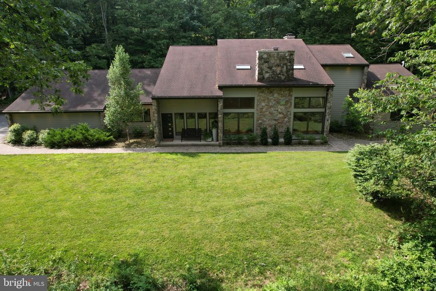 Prepare to Be Star Struck.  Tucked away on 5.64 serene, wooded acres, this stunning stone & Hardie Plank contemporary-style home offers the perfect blend of upscale living & uncompromising privacy.  Located within the peaceful Pantops community, but without restrictions, as this rare property is excluded from the HOA.  Accessed by a winding private driveway, this one-of-a-kind retreat boasts 7,198 square feet of beautifully finished living space across three expansive levels, just 7 miles from downtown State College & Penn State University, within the State College Area School District.  A major professional landscape renovation enhances the already striking curb appeal with deer-resistant plantings, river rock & LED recessed lighting surrounding the exterior. Step into the grand two-story foyer, where a gorgeous custom-crafted hardwood curved staircase & elegant chandelier set the tone for the refined elegance found throughout.  At the heart of the home is the breathtaking Great Room, a dramatic, light-filled space featuring a soaring ceiling, second-floor loft overlook, a floor-to-ceiling fireplace with gas insert, a wall of windows & hardwood flooring. Entertain with ease in the formal dining room, while the living room offers a wood-burning fireplace, custom-built-ins, rich hardwood floors & peaceful wooded views that bring the outside in.  The gourmet kitchen is outfitted with solid surface countertops, double wall ovens, cooktop, Sub-Zero refrigerator, a large island with breakfast bar, abundant cabinetry, new French doors & a delightful dining area. A sunny four-season sunroom adds flexible space for relaxing or entertaining, along with a mudroom/laundry room conveniently located on the main level.  The main-floor primary suite is a private retreat featuring a vaulted ceiling, walk-in closet & a fully renovated en suite bath with a water closet, dual vanity, tile flooring, walk-in shower & soaking tub, all designed to showcase tranquil woodland views. Also on the main level is a second bedroom & a full bath, perfect for guests & a third bedroom currently used as a home office.  Upstairs, a spacious loft overlooks the Great Room, 2 additional bedrooms, each with full private bathrooms, one even includes a huge walk-in closet/bonus room for added flexibility.  The finished lower level is built for entertaining, featuring a sprawling recreation room, bar area, wood-burning fireplace & an updated half bath, the perfect space for hosting Happy Valley game day gatherings.  Step outside to your own private backyard oasis with a sparkling heated in-ground pool, massive paver patio & built-in fire pit, an idyllic setting for summer entertaining or peaceful evenings under the stars.  For car lovers & hobbyists, this property offers both an attached 3-car garage (965 sq ft) and a detached 2 car garage (2,000 sq ft), built in 2000. Additional upgrades include 400 AMP electric service, a 22kW whole-house automatic generator, and fresh exterior & interior paint throughout.  This extraordinary home is more than a residence—it’s a private sanctuary designed for both everyday luxury & unforgettable entertaining.  Don’t miss your opportunity to experience this exceptional property in person.