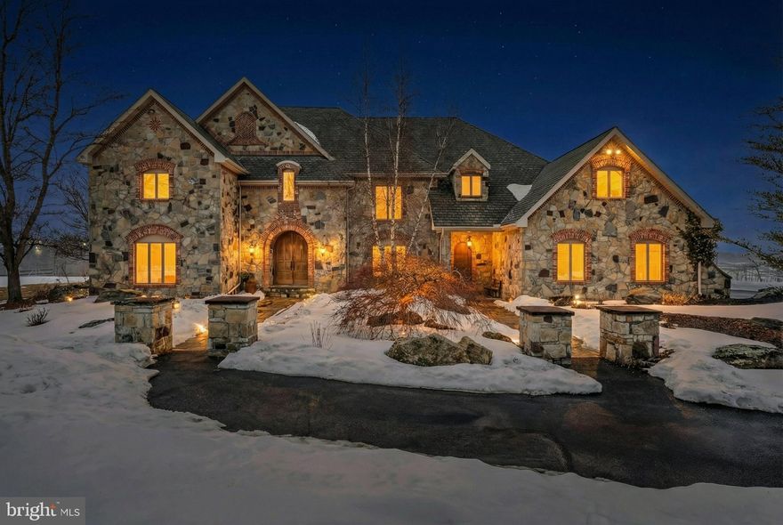 Behind a winding 2,400-foot paved drive, 72 acres of rolling countryside unfold into one of the most distinctive private estates in the Poconos. The approach alone sets the tone — a gradual transition from the outside world into a landscape defined by open pasture, mature woodland, and panoramic views that stretch uninterrupted across the horizon. The setting feels expansive, private, and remarkably self-contained.

Pohopoco Creek winds naturally through the acreage, shaping a distinct ecological corridor of mature riparian trees, native wildlife, and seasonal movement. The presence of water introduces environmental depth rarely found at this scale — enhancing privacy, biodiversity, and long-term land value while creating a setting that feels both protected and alive.

At the heart of the estate stands a 6,400 square foot French-inspired stone residence designed with structural integrity and architectural permanence in mind. Full masonry stone construction, exposed timber trusses, arched architectural openings, and a soaring two-story great room establish immediate presence. A dramatic floor-to-ceiling masonry fireplace anchors the main living space, while slate and hardwood flooring, artisan millwork, and solid wood trim reflect craftsmanship over trend.

The kitchen was designed for scale and gathering, featuring generous prep areas, professional-grade appliances, and open sightlines to the surrounding living spaces. It is equally suited for intimate family dinners or large-scale entertaining. The private primary suite offers balcony access overlooking the acreage, creating a quiet retreat within the estate. Multiple living areas, including formal and informal gathering spaces, provide flexibility for hosting, work-from-home needs, or multi-generational living.

Beyond the residence, the land continues to deliver. Established barns, paddocks, fencing, and agricultural infrastructure support equestrian or boutique farming pursuits. Currently home to a successful alpaca operation, the property demonstrates proven livestock capability while maintaining its luxury estate presence. The acreage offers a rare combination of usable pasture and natural woodland, allowing for both productive agricultural use and conservation-oriented enjoyment.

A separate commercially zoned parcel within the property boundaries provides additional long-term flexibility, opening the door to strategic future opportunities while preserving the estate’s privacy and scale.

The grounds also feature an in-ground pool positioned to take advantage of the surrounding views, a four-car attached garage with generous bay depth, and extensive paved access throughout the property.

This is not simply acreage paired with a home. It is a privately positioned legacy estate where land, water, architecture, and infrastructure align. Opportunities offering this level of scale, environmental diversity, and structural quality rarely become available in the region.

For those who value autonomy, land ownership, and enduring construction over trend-driven living, 216 Merwinsburg Road represents a generational acquisition.