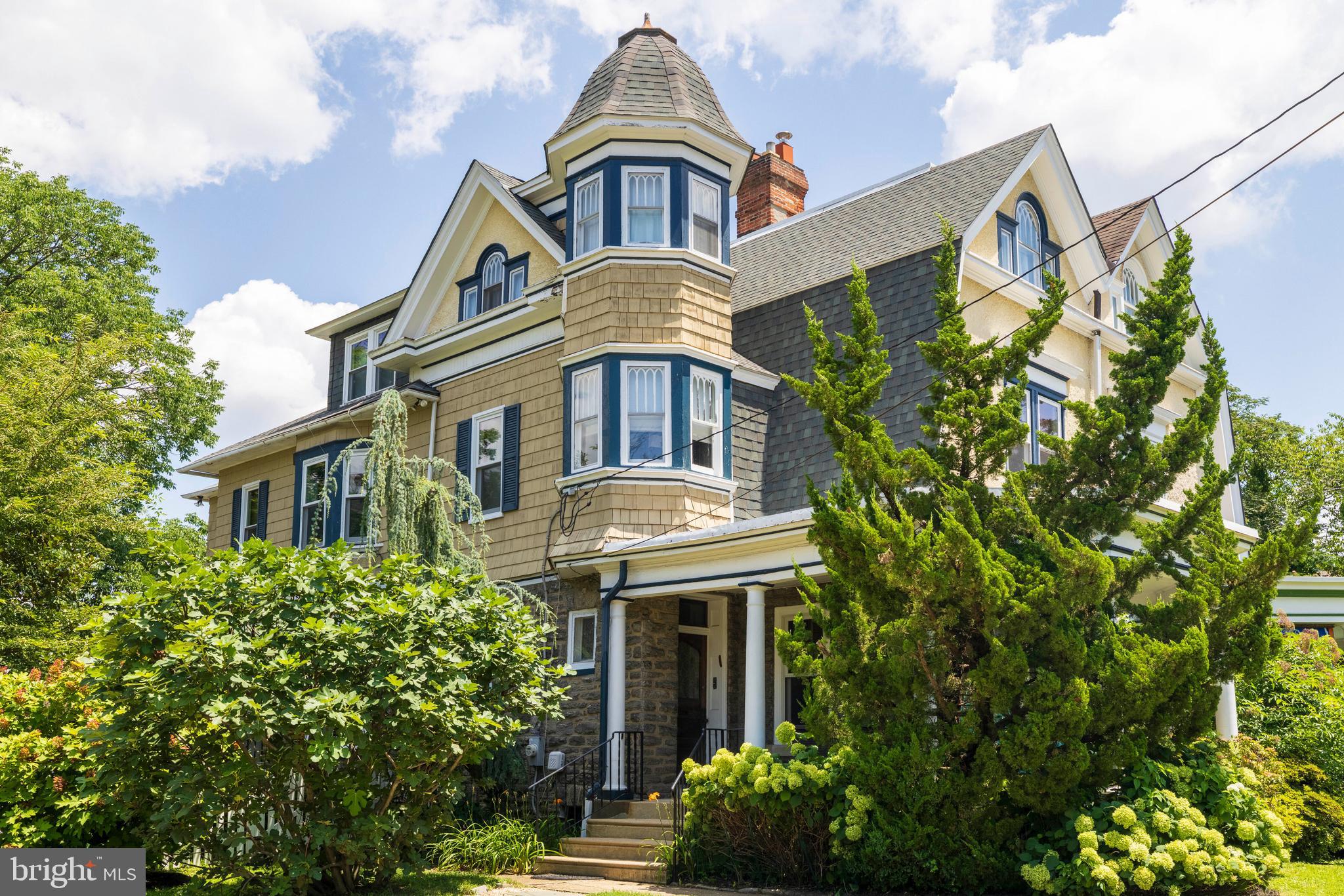 Elkins Park beauty! Charming, gorgeous 5 bed/3.5 bath home on a lovely block with parking and character for days! The covered front porch leads to the beautiful vestibule with original ceramic tile and stunning original wooden doors with glass. Upon entering you'll notice the grand staircase and the large living room with 14' ceilings and plenty of space for company. The separate dining room features two windows and a side door, allowing tons of light to flood in. There is a butler's pantry with a floor to ceiling storage cabinet off the dining room. Beyond that you will find a spacious eat-in kitchen with new dishwasher and fridge. Off the kitchen there is a lovely sunroom that opens up to the back deck that's perfect for grilling and relaxing. This level also features a powder room for convenience. There is a back staircase as well that goes from the first floor to the second. The grand tour continues as we head up to the second floor. The front bedrooms serves as the primary suite with built-in storage closets, a separate room that can be a dressing room or office and a full bath. The two other bedrooms on this level share a jack and jill style full bathroom. On the third floor you'll find two more large bedrooms (one is being used as a 2nd family room) and a full bathroom. Enjoy gardening and sitting by the fire pit in the lovely backyard with storage shed and a new back fence. The basement has tons of storage, a spare refrigerator and washer/dryer. This home truly has it all- loads of original details, hardwood floors, high ceilings, tons of natural light, central air and tons of charm. The location is fantastic as well- lovely block, close to the train station, shops, parks, public transportation and so much more. Move right in!