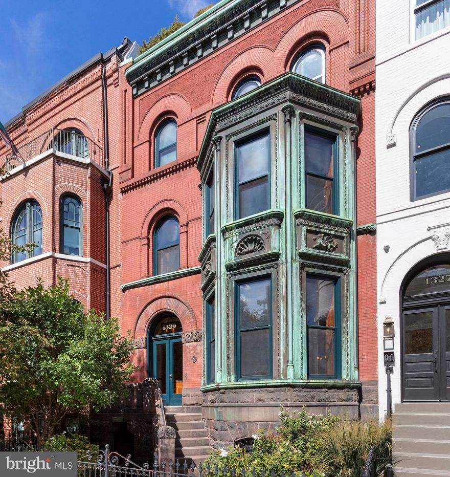 Architectural Digest-Worthy, Logan Circle Grand Dame!

With its awe-inspiring two-story copper bay window and historic details throughout, this 7 bedroom, 7 full baths, 3 half baths residence is the perfect marriage of past and present.

Originally constructed in 1892, 1329 R Street has been fully renovated with an eye toward preserving and restoring the home’s historic elements while updating it for luxurious modern living. Offering more than 6,500 square feet of meticulously restored living space, key features of the extra-wide 25’ house include an eat-in chef’s kitchen, dual primary suites, wood paneled library, three restored fireplaces, and an elevator providing direct access to every level including the penthouse and an expansive roof deck with outdoor kitchen, hot tub, and monument views.

With an impressively intricate fruitwood staircase welcoming its guests, the main level has a double-parlor layout with a dedicated living and sitting room separated by pocket doors, each graced with its own wood-burning/gas fireplace. These rooms connect to the main dining room that lead into an expansive Chef’s kitchen with an eat-in island and breakfast area, high-end appliances sure to please the most discerning entertainer, a separate beverage refrigerator, ice-maker and two dishwashers.

Connected to the kitchen by a separate modern staircase, the terrace level holds a family room plumbed for a catering kitchen, a half bath, a bedroom with en-suite bathroom, a mudroom with laundry, an AV closet and a wine refrigerator. The upper levels feature expansive living spaces with the second floor holding one of two primary suites, a handsome wood-paneled library with its original fireplace and bay window, a guest bedroom and a large bathroom. A “talking tube” with the home’s original keys hanging from it subtly sits outside the library, juxtaposing the residence’s past with its contemporary surroundings.

The home’s third level includes the second primary suite with sleek built-ins, motorized blackout shades, and a spa-like bathroom with radiant heated floors, an oversized tub, double vanity sinks, and a dual-headed steam shower with body sprays. This level is complete with a wet bar that holds a sink, beverage refrigerator, ice-maker, dishwasher, and stacked laundry, perfectly sited between a family/media room and two bedroom suites

One of this residence’s many wow-factors is ascending by modern stair or elevator to the penthouse sunroom with half bath that opens to a massive rooftop deck. With over eleven hundred square feet of entertaining space and monument views, this outdoor oasis holds a kitchen, gas grill, a stainless-steel hot tub, a spa shower, and gas fire table.

Renovated in 2017 and preserved as a single-family home, 1329 R St NW was reborn with an eye towards preserving its historic elements while thoughtfully inserting hallmarks of modern living. It is fully networked throughout with Cat 6 cable, whole-house Sonos sound system, Lutron programmable lighting, a security system that includes multi-warning sensors, an all-level access home elevator, 2 car secured parking and Tesla charger.

The original sign of Dr. Westanna Byrom, the first Black female dentist to open her office doors to DC residents marks the entrance to a nearly 800 square foot fully renovated and legally separate 1 Bedroom English basement apartment which could generate rental income or be used for extended family or staff.

1329 R St NW offers a unique opportunity to own a truly functional and architecturally significant residence meticulously maintained and restored for the contemporary tastes of today’s family.