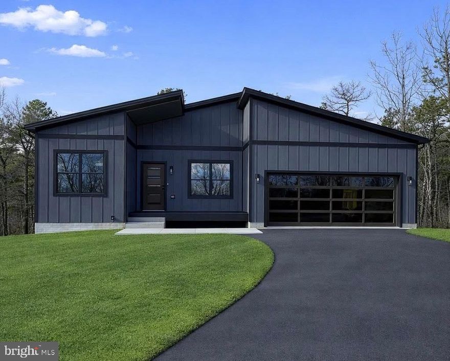 READY NOW!!!!    This stunning new construction Mid-Century Modern home sits on a spacious 0.86-acre lot in the desirable Woods Resort, offering beautiful mountain views!  The Berkeley floorplan provides over 1,800 finished sq. ft. on the main level, plus an 1,800 sq. ft. walkout basement with 9’ ceilings   —   ideal for future living space or additional storage. The exterior will feature upgraded dark grey LP siding paired with a rich brown garage door and matching brown front door, creating a warm, refined modern look that perfectly complements the natural setting. Inside, you’ll find luxury vinyl plank (LVP) flooring throughout, stainless steel appliances in the kitchen with a spacious kitchen Island, and a cozy living room with a fireplace framed by a black wainscoted accent wall. The spacious primary suite boasts another bold black wainscoted accent wall and an en-suite bathroom complete with a sliding barn door, custom tile shower, and modern finishes.
Step outside to a 26’ x 10’ composite Trex deck with sleek cable railing, ideal for relaxing, entertaining, or taking in the serene, wooded views. This home is eligible for Class A Woods Resort Membership, granting access to indoor/outdoor pools, spa, sauna, fitness center, golf courses, tennis courts, and more (optional annual fee through the resort).
Don’t miss the opportunity to own this stylish, upgraded, and thoughtfully designed home in a premier resort community! Garage Door and Front door will be brown.