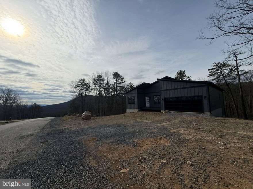 READY NOW!! This stunning new construction Mid-Century Modern home is nearly complete and sits on a spacious 0.86-acre lot in the desirable Woods Resort, offering beautiful mountain views. The Berkeley floorplan provides over 1,800 finished sq. ft. on the main level, plus an 1,800 sq. ft. walkout basement with 9’ ceilings—ideal for future living space or additional storage. The exterior will feature upgraded dark grey LP siding paired with a rich brown garage door and matching brown front door, creating a warm, refined modern look that perfectly complements the natural setting. Inside, you’ll find luxury vinyl plank (LVP) flooring throughout, stainless steel appliances in the kitchen with a spacious kitchen Island, and a cozy living room with a fireplace framed by a black wainscoted accent wall. The spacious primary suite boasts another bold black wainscoted accent wall and an en-suite bathroom complete with a sliding barn door, custom tile shower, and modern finishes.
Step outside to a 26’ x 10’ composite Trex deck with sleek cable railing, ideal for relaxing, entertaining, or taking in the serene, wooded views. This home is eligible for Class A Woods Resort Membership, granting access to indoor/outdoor pools, spa, sauna, fitness center, golf courses, tennis courts, and more (optional annual fee through the resort).
Don’t miss the opportunity to own this stylish, upgraded, and thoughtfully designed home in a premier resort community!