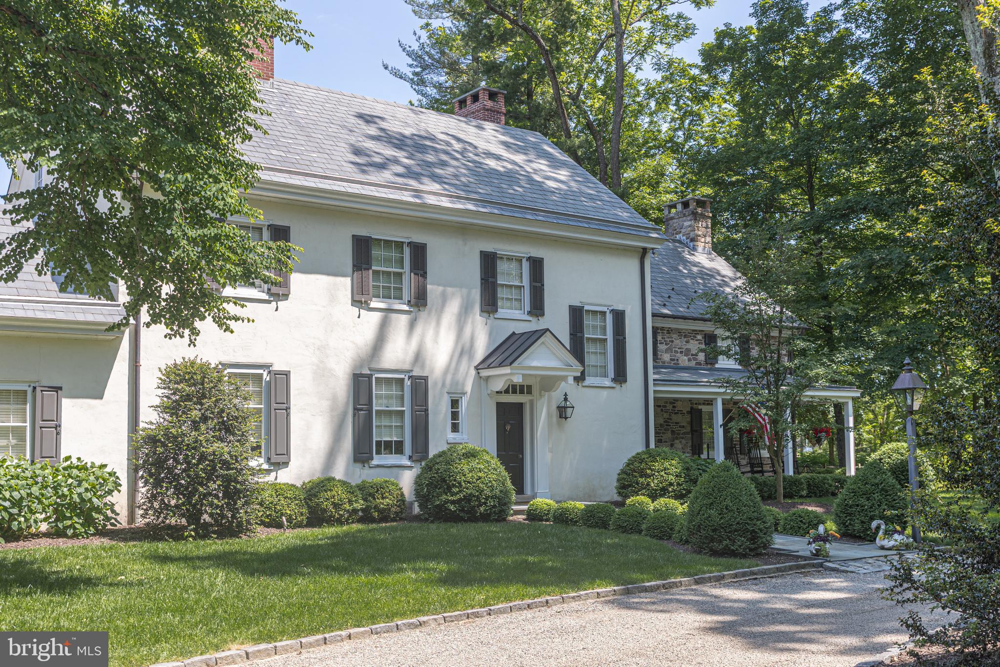 Nestled on 7.5 acres, this custom-built reproduction farmhouse surrounded by towering trees and bordered by open space, blends refined craftmanship with modern comforts. From the moment you arrive through its private stone walled entranceway, the covered front
porch sets the tone. This 5 bedroom, 4 full and 2 - ½ baths residence has been elegantly refreshed and thoughtfully updated throughout. Step inside to discover custom paneling and wainscoting, hardwood floors, mostly throughout, and plenty of sun-drenched rooms on the first floor. As you enter the spacious foyer with its half bath, a stately living room with a wall of built-ins that surrounds a fireplace lies ahead. Immediately to the left of the foyer is the family room complete with a stone fireplace. This room flows seamlessly into the gourmet kitchen that is outfitted with high-end stainless-steel appliances, custom-designed cabinetry and a large island with counter seating. Just off the kitchen is the formal dining room with window box seating that overlooks the picturesque backyard and provides outdoor access onto a flagstone patio. Also on this level is a private office and a bedroom suite with an en-suite bath and 2 cedar closets, perfect for an au pair. In addition, there is an over-sized laundry/mudroom with its own half bath. Upstairs is the master bedroom suite with a vaulted wood ceiling, a walk-in-closet and an en-suite bath with dual vanities and an oversized walk-in shower. The second floor also offers three spacious bedrooms, one with an en-suite bathroom and walk-in closet, while the two remaining bedrooms access the hall bath. The third floor is a new open high-ceiling space with large windows perfect for an office, entertainment or game room or additional bedroom with sitting area. An unfinished walk-out lower level with multiple rooms provides ample storage with direct access to the outdoor patios, pool, and gardens. Beyond the interior, discover outdoor living at its finest. Step outside and onto one of three beautiful bluestone terraces, perfect for family gatherings and barbeques or to just take in the gorgeous long-distance views the property has to offer. In close proximity to the home and a lovely in-ground pool is a newly built detached carriage house which provides on one side an outdoor covered space perfect for alfresco dining and on the other side a 3-car garage. Above the carriage house is flex space of about 1,160 s.f. that has been outfitted with a full custom designed kitchen, Wolf and Subzero appliances, living room, bedroom with its own full bath and laundry room, perfect for multi-generational living or guest accommodations. Whether you're enjoying the peaceful surroundings or heading out to nearby spots like New Hope or the Delaware River, you will enjoy this home's blend of tranquility and convenience. This property offers privacy and a one- of- a- kind setting within the award-winning New Hope Solebury school district. An extraordinary opportunity to own a charming residence in one of the region's most sought-after locales. Schedule your private tour today.