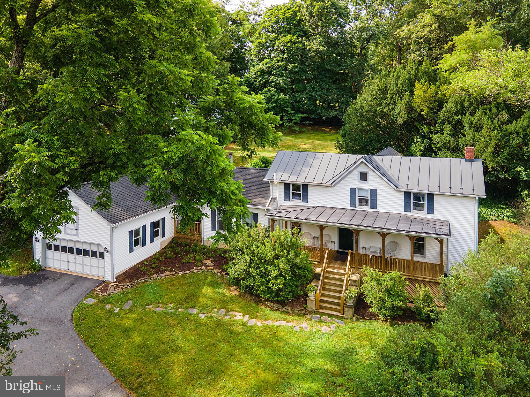 Welcome to your new home in Round Hill—a charming blend of historic character and modern comfort. Originally built in the 1900s, this inviting farmhouse welcomes you with a traditional wide front porch perfect for gathering with friends or sipping your morning coffee. Step through the front door into the classic center hall foyer where a beautifully carved wood newel post sets the tone for the home’s timeless details. To the left, the formal dining room features original hardwood floors and chair railing - while to the right the formal living room offers fresh new carpet and great natural light. At the rear of the home, the kitchen opens to a generous breakfast room—ideal for casual meals or entertaining. The kitchen includes a peninsula with seating for three, unique greenhouse window over the double sink, plus access to a private stone patio for al fresco dining. The heart of the home is the two-story, light-filled family room with a wood-burning fireplace, creating a cozy space to gather year-round. From here, step out to a second stone patio or take the covered walkway to the detached two-car garage. A powder room off the foyer completes the main level. Upstairs, the spacious primary suite includes a private sitting area, walk-in closet, full bath, and its own balcony—an ideal retreat. Two additional bedrooms, both with original hardwood floors share a full hall bath. The fully fenced backyard features mature trees and garden beds—perfect for pets, play or your next garden project. Fully renovated in the 1990's by well known local architect Beckham Dickerson. Tucked just south of the village of Round Hill and only minutes to Route 7 this location offers small-town charm with unbeatable convenience. Don’t miss your chance to own a piece of history with all the comforts of today!