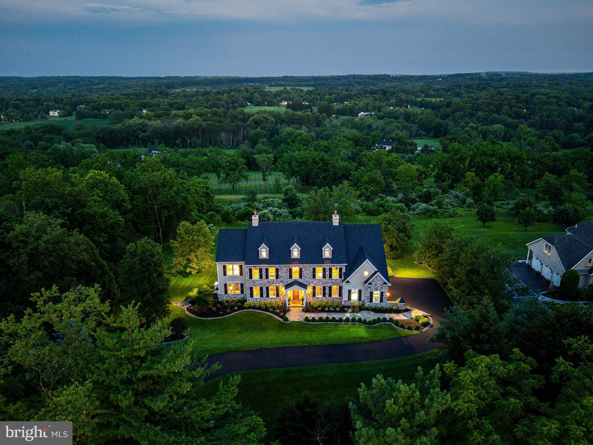 Welcome to 5835 Ridgeview Drive, a custom-built estate home in the heart of Bucks County and within the Blue-Ribbon Central Bucks SD. Across from a preserved farm and just 4-minutes from a Texas Longhorn sanctuary, enjoy your morning coffee with stunning sunrises and beautiful views of the valley. This home exudes consummate craftsmanship and meticulous attention to detail with three- and four-piece crown molding, radius corners, solid core doors, tongue and groove quarter sawn white oak hardwood floors with mahogany inlays. This home is in showcase condition. Screened from the road and situated above the valley, you are greeted with breathtaking views for miles. Entering the foyer with 20-foot ceilings and finished with a ceiling medallion and four-piece crown molding, you will immediately enjoy front-to-rear views of the home highlighted with a magnificent circular staircase. The living room is finished with three-piece crown molding, hardwood floors, mahogany inlays and a gas fireplace. The large dining room features hardwood floors, ceiling medallion, understated ceiling moldings, wainscoting and three-piece crown molding. The spacious custom gourmet kitchen is a culinary dream with a center island seating five, granite countertops, warming drawer, under counter microwave, Monogram 48” refrigerator with a 6-burner dual fuel double oven, pot-filler and a wine refrigerator. The kitchen is functional and beautiful. A large pantry offers plentiful storage. At the rear of the home is the morning room with a vaulted ceiling three walls of windows and is bathed in sunlight from morning to evening. Entering from the oversize three car garage is a tiled mudroom with cabinets, sink, four individual storage cubbies and a half bath. Off the morning room and kitchen is the great room with 20-foot ceilings, a built-in bookcase, a wall of windows and a stone gas fireplace. A half bath is off the short hall leading back to the foyer. The back porch is warmed in the fall and winter with a stone gas fireplace , outdoor speakers and may be accessed from the family room or office. Entering the office is a wet bar with a stunning granite countertop, under-counter refrigerator and plenty of cabinetry. The office provides privacy while still close to family activities and features a drawered built-in bookcase with views of the front, back and side yards. Additional features on the first floor are hardwood rear stairs with new carpet in the family room as well as the rear stairs. Upstairs, the primary bedroom suite is a private sanctuary with high ceilings, a sitting area plus a dressing/make-up area. The primary bathroom includes a Jacuzzi whirlpool tub, limestone vanity top with his and her sinks, walk-in shower with body sprays and private commode. There are two substantial custom closets and a private balcony overlooking the valley. The second floor also features three additional en-suite bedrooms that are extraordinarily spacious, all featured with three-piece crown molding and a spacious laundry room. An unfinished third floor with windows accessed via hardwood stairs with plumbing roughed in has great potential for an additional bedroom, exercise or game room. The finished lower level features a gathering room, bar/kitchen area, TV room, sizable bedroom, full bath and a huge storage area. Windows across the rear of the house allow an abundance of sunshine with a French door opening to the landscaped yard makes the lower-level feel like it’s a first floor and makes for a perfect in-law suite or au ‘pair living area. Accessed from the outside and below the mud room is a large, secured/alarmed storage room allowing plenty of space to store outdoor furniture and gardening supplies. This home makes you feel like you are on vacation every season of the year. Minutes to Doylestown or New Hope with Philadelphia 75 minutes south and New York 95 minutes north, this home is convenient for everyone.