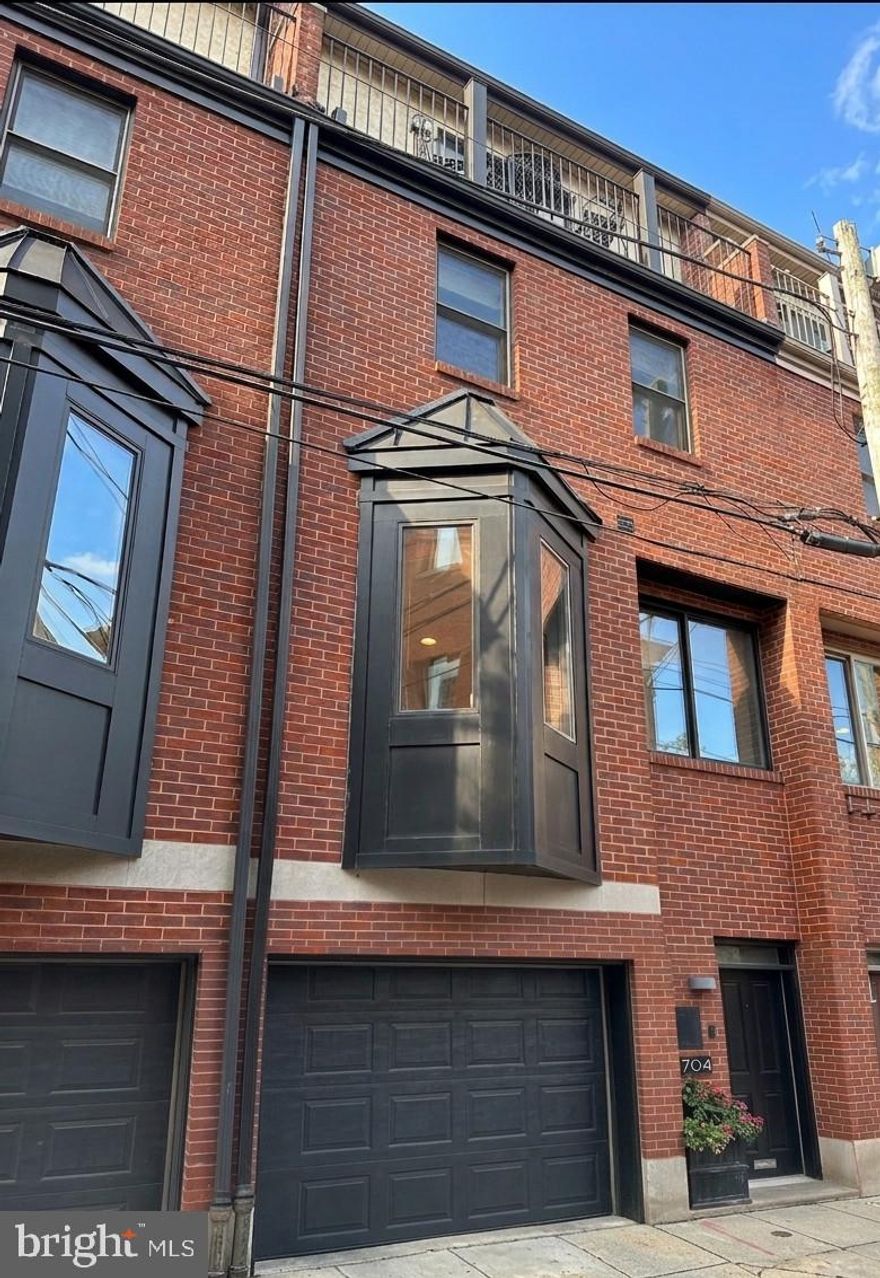 A beautiful, 2,500+ square-foot contemporary four-bedroom townhome with GARAGE parking, situated steps from Rittenhouse Square, overlooking a private pocket park. The ground level features a tiled entry foyer, a powder room, and a large bedroom. This floor also provides interior access to the attached garage, which includes a secondary full-sized refrigerator and additional storage. You'll also find solid wood floors and doors throughout most of the home. The second floor is a dedicated open-concept living space with oak hardwood flooring, recessed lighting, and a gas fireplace. The kitchen is equipped with cherry cabinetry, honed granite countertops, stainless steel appliances, a wine refrigerator, gas cooking, and a bay window with banquet seating. Sliding glass doors lead from the living area to a large deck. The entire floor just flows from one end to the other, which is perfect for entertaining. On the third floor, two bedrooms (one being used as a den) with custom closets share a gracious hallway bathroom. This level also contains a laundry area with a full-sized washer and dryer. The top floor is reserved for the primary suite, which features vaulted ceilings, a second gas fireplace, and custom closets. Sliding doors open to a private balcony with Center City skyline views. The primary bathroom includes a dual vanity and a newer, large glass-enclosed walk-in shower.