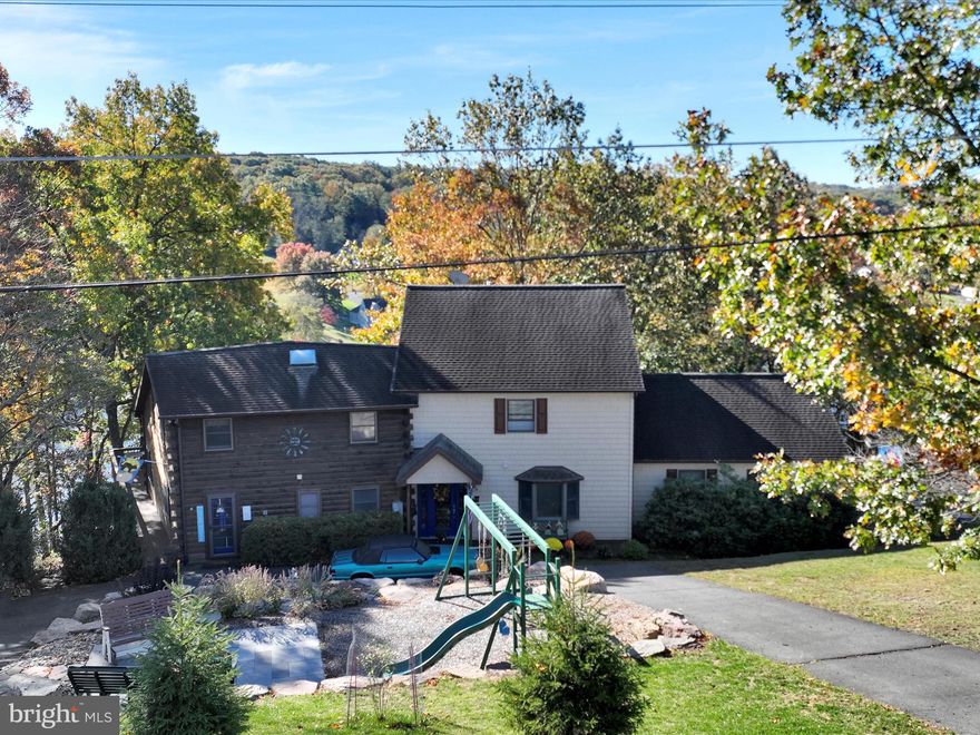 Impressive investment opportunity! Plant seeds for tomorrow. One-acre + a 3,842 square foot lakefront home significantly reduced due to the Lake Wynonah Dam rehabilitation project. Discover your own private sanctuary on a spectacular one-acre lot that perfectly blends rustic charm with modern comfort. This 3,842 square foot partial log home showcases five bedrooms and three and a half bathrooms, thoughtfully designed across multiple levels to maximize both space and stunning views. The main floor welcomes you with gorgeous hardwood flooring and recessed lighting throughout. The heart of the home features a functional kitchen flowing into the dining area and living room, where a cozy propane fireplace creates the perfect gathering spot. Two comfortable bedrooms and two full bathrooms complete the main level, along with a family room and convenient access to the oversized two-car garage. Upstairs, the spacious primary bedroom with spectacular views of the pristine natural setting includes an en suite bathroom and two generous walk-in closets. Two additional bedrooms and another bathroom provide plenty of space for family and guests.The large unfinished basement offers endless possibilities for customization, while five separate heating and cooling zones ensure year-round comfort. Recent updates include a new air handler and a four-year-old on-site septic system. Radon mitigation system installed. Step outside to your personal paradise featuring a paved pathway leading to the lower level, complete with a newer bulkhead and spacious dock. The large deck includes a screened area for relaxation, while the firepit area creates magical evening gatherings. The newer addition with vinyl shake siding seamlessly complements the original log construction, creating a truly unique and inviting retreat. Lake Wynonah is a gated, HOA community. Amenities include: business office/gathering room/library, lodge w/dining and bar, social clubs, electric boating, fishing,  paddleboarding, tennis, pickleball, several parks/pavilion, basketball courts, horseshoe pits, 2 pools, hiking, and natural wildlife. Groups and events include: Active Civic Association, Dances/Concerts, Book Group, Pinochle Group, Volunteer Programs, Fish & Boat Group. *Some photography displays Lake Wynonah at full pool. Please call the Lake Wynonah Business Office for updates regarding the Lake Wynonah Dam. Boating is restricted to electric/trolling motors only while the Lake Wynonah Dam is being rehabilitated. Please call the Lake Wynonah Business Office for updates on the "big lake"/Lake Wynonah Dam rehabilitation project and probable future assessment.