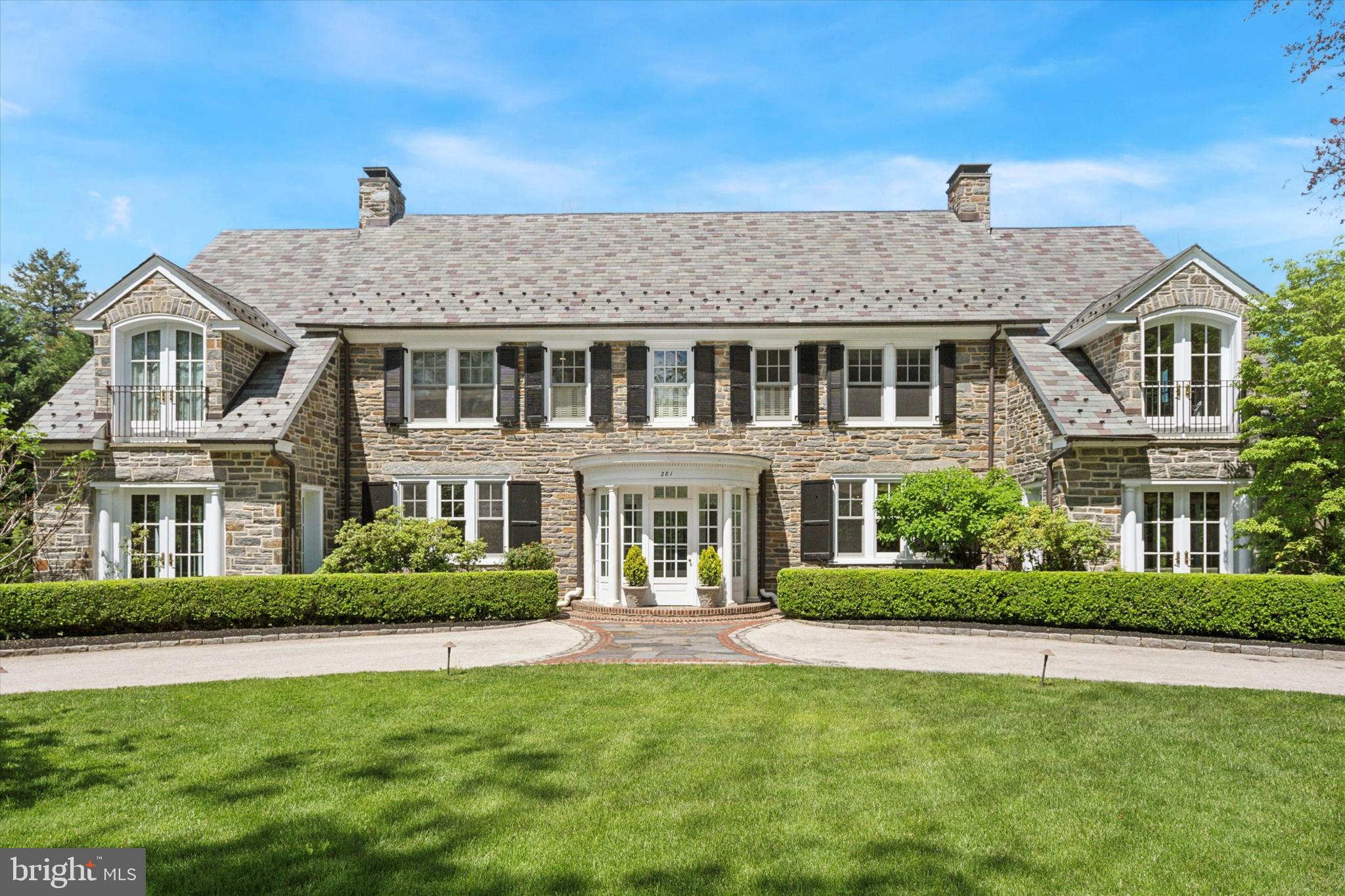 Come home to tasteful luxury in an exceptional location! The unique property at 281 Winding Way offers a lifestyle without compromise: The magnificent 8,700+ sq.-ft., 6BR, 5/2BA residence combines classic 1925 stone construction with a full interior renovation that incorporates such contemporary conveniences as a smart house system and an elevator that reaches all five levels. From the circular stone driveway in front to an in-ground pool/hot tub surrounded by trees, the 1.1-acre property offers the epitome of gracious suburban living while putting the delis, restaurants, shops and services of Merion Station and Narberth borough within walking distance; Center City Philadelphia is minutes away by rail or car.
A slate roof & copper tops off the stately stone façade. Beyond the covered portico, you’re immersed in quality. The interior was completely renovated in 2012 with meticulous attention to detail, with Venetian plaster walls and custom millwork, Marvin windows, and hardwood doors with Baldwin brass hardware throughout. The first level above ground features teak herringbone hardwood floors in the foyer, living room and dining room. French doors flanking the living room fireplace lead to a light-filled sunroom with slate floor and multiple double doors opening to back and side terraces. The formal dining room has a fireplace and unique moldings and millwork, and provides access to the family room and to the kitchen and breakfast nook.
The chef’s kitchen, renovated more recently 2016, features variable width reclaimed oak floors, an island with seating and storage, white subway tile walls, and all-white custom cabinetry with black soakstone countertops. A palladium window adds a cheery touch over the extra-deep sink, and an oversized stainless-steel fridge/freezer, dual ovens and 6-burner range provide convenience no matter who is cooking or for how many. An arched doorway leads to the side yard. Off the kitchen, a sitting room has one of two powder rooms on this level and elevator access.
On the second above-ground level, via elevator or stairs from the foyer or kitchen, escape to a spacious primary suite with hand-painted doors, antique Italian sconces, arched French doors opening to a balcony, a dressing room with a design custome closets, and a luxurious bath with imported dual vanities and mirrors, whirlpool tub with a custom surround, and spacious shower. Also on this level are three large bedrooms, one of which can be accessed via elevator and shares a Jack-and-Jill bath with a second bedroom; a third has front and side balconies. The last room in the second floor has an in-suite luxury bathroom. The third level has a third bedroom and full bath, and two large rooms that could serve as a home gym, TV room or playroom.
A finished level below ground home theater, wine cellar with dedicated HVAC system, recreation room, full bath and access to elevator and two-car garage.. For maximum comfort, the home has a 110-gallon water heater and six HVAC systems for the living spaces.
Located on a quiet side street and surrounded by other grand homes, this exquisite property is within the top-ranked Lower Merion School District, close to renowned private education institutions. Whether you prefer culture and nightlife or nature, you are just 6 miles from Center City, a mile from the Cynwyd Heritage Trail Cynwyd Station Park trailhead and close to Merion Botanical Park and dozens of other parks and recreational facilities in the township and all that Philadelphia and the lower Main Line have to offer.