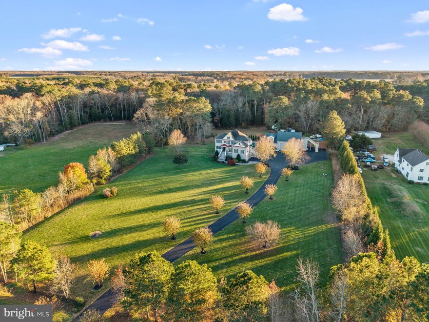Welcome to the Longridge Road Ranch—a private 7.24-acre luxury estate offering over 8,000 sq. ft. of living space and a lifestyle defined by quiet privacy, elevated comfort, and exceptional versatility. Tucked deep into a serene rural setting, the home is thoughtfully positioned for those seeking space to live fully, host expansively, or create a retreat-style environment—all while maintaining convenient access to everyday amenities. Designed and custom-built by ScottyB Sales & Designs in 2007, this residence is intentionally configured for multi-generational living, income-producing potential, retreat use, or private estate living. Multiple independent living areas allow family members, guests, and long-term visitors to enjoy both connection and privacy under one roof. The first-floor private suite includes a bedroom, full bath, full kitchen/dining area, laundry room, a dedicated movie theater room, and a sunroom overlooking the custom propane-heated L-shaped pool. The second-floor in-law quarters offer a living room, kitchenette, bedroom, full bath, and private laundry. The primary living spaces are warm, inviting, and designed for daily comfort and elevated entertaining. The great room features a propane fireplace and flows into the formal dining room, living room, sunroom/office, and a beautifully crafted kitchen with breakfast nook and wet bar.  The owner’s suite is an expansive retreat, complete with tray ceiling, propane fireplace, oversized multi-head walk-in shower, whirlpool soaking tub, private water closet, dressing-style walk-in closet, and direct access to its own third-floor deck.  A spacious guest bedroom above features jack and jill bathroom with separate vanities.  a A finished, climate-controlled fourth level offers flexible use for play, hobby, office, or storage needs. The estate’s outdoor living environment delivers a private resort experience. The custom propane-heated pool is surrounded by 2022 Polyaspartic-coated patios and walkways, complemented by an outdoor jacuzzi and a tranquil fish pond feature integrated beneath the rear staircase. The fully fenced pool and recreation area provide the perfect backdrop for hosting and relaxation. A defining highlight of the property is the detached luxury garage complex—a 40'×21'×12' heated workshop paired with a 22x20x12 finished entertainment lounge/man cave complete with full bath, gym, recreation space, and bar. Above, a private apartment offers its own entrance, living space, kitchen, bathroom, 12'×16' elevated deck, and 40'×10' pool-view porch. Fully separate from the main residence, this structure is ideal for extended family, guest lodging, caretaker housing, income/rental use, wellness studio, STR retreat suite, or business headquarters. Additionally, three large heated indoor/outdoor dog kennels with fenced runs provide exceptional options for pet care, hobby breeding, or small-scale boarding. Well-planned systems support comfortable and efficient long-term living: five new HVAC systems (2023), Rinnai tankless propane water heater (2021), 72 owned solar panels with monitoring, multi-zone irrigation across lawn areas, blacktop driveway recoated in 2025, dual-zone water treatment system, and a new pool pump in 2025. Though enveloped in privacy, the property remains centrally connected: Rural living at its finest, but only minutes from downtown Salisbury, Rt. 50, 5 minutes to the Rt. 13 / Rt. 50 Bypass, and less than 30 minutes to Ocean City, Fenwick Island, and Bethany Beach, bringing coastal recreation, dining, nightlife, and travel access within easy reach. This is not simply a residence—it is a self-contained estate capable of supporting multi-generational family living, short-term rental or investment models, organizational retreats, private wellness and creative spaces, or a sanctuary for those seeking privacy without compromise. Here, luxury, comfort, and possibility converge.