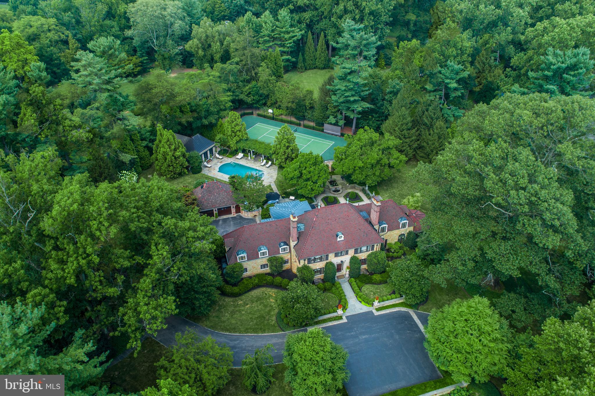 Virtual tours are available! No in-person tours until the shelter in place order is lifted. Please contact the Listing Agent for more details. Youtube Aerial Video Tour: https://youtu.be/Qevq5fvDP2w. Exceptional living awaits the discerning buyer seeking the ultimate sophisticated Main Line estate property, on one of the most exclusive streets in Lower Merion Twp. Located in premier Northside Bryn Mawr, this magnificent classic stone home sits on over 2 acres of breathtaking gated grounds. Mature trees, gorgeous gardens & tranquil garden pools provide the utmost beauty and privacy. Exclusive recreation is yours with the amenities of a fabulous pool & spa, well-appointed guest house & regulation-size tennis court for perfecting your game. This truly rare gem, built in 1938, epitomizes elegance in every way. The prestigious residence with Ludowici tiled roofs and multiple outdoor terraces & living spaces has been meticulously restored and fully renovated, down to the last stunning detail.Unparalleled luxury continues to unfold inside, with a gracious front to rear entrance hall that opens to the terrace & gardens. Exquisite fireplaces, millwork, wainscot paneling, hand-painted walls & restored oak floors with inlay enhance the tremendous character. Entertaining is at its grandest in formal living & dining rooms. Hosting continues in a substantial sunroom with exposed stone floor & walls, which includes a custom built-in bar & media cabinetry, and offers panoramic views of the gardens. Read & relax in the cherry-paneled library with fireplace. The custom chef s kitchen features top-of-the-line finishes & appliances and a butler s pantry. Adjacent is a breakfast area & spacious family room with radiant heated flooring, windows on all sides & French doors that open onto the terrace, outdoor kitchen & gardens. Formal & informal powder rooms + a convenient mudroom complete the expansive main level. The staircase brightened by a large window at the 2nd level landing ascends to tranquil sleeping quarters. A luxurious retreat, the master suite has a vaulted ceiling, sitting area, generous fitted walk-in closets & spa-like marble bath. Three additional spacious bedrooms, one en-suite, and a renovated marble full bath accommodate family & guests. Perched on level 3 is a private 5th BR suite with a walk-in cedar & other closets. The renovated walk-out lower level is a haven all its own boasting a wood-paneled media room with stone wood-burning fireplace, fully-equipped gym, wine room, wrapping room, laundry, powder & storage rooms. Ridgewood Road s finest home also includes a full-property generator, attached 2-car temperature-controlled garage, detached 2-car heated garage & location beyond compare. This proper Main Line estate offers the very best of town & country living.