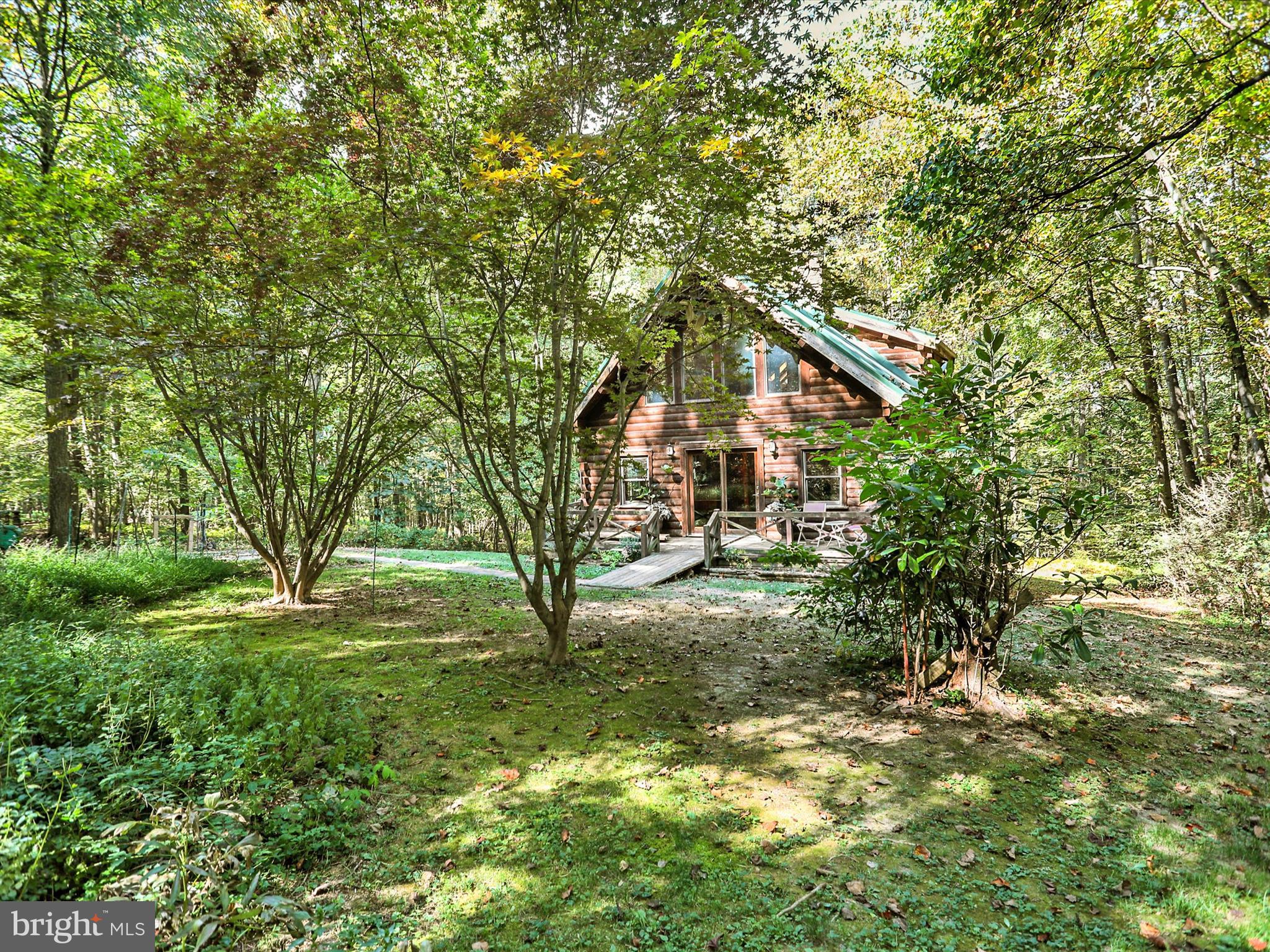 If you have been dreaming of a place to escape the hustle and bustle, this log cabin-style home might be exactly what you've been waiting for! Set on almost 2.5 wooded acres it provides privacy, peace and a genuine connection to nature. With 3 bedrooms and 2 full baths there is plenty of room for family and friends to gather while still maintaining a cozy comfortable feel. Picture yourself enjoying your morning coffee on the porch or deck while watching the wildlife or spending a quiet evening outside listening to the sounds of nature. Every season will bring its own charm to this home. Inside at the heart of this home is the large stone fireplace --perfect for curling up in the cooler months. Wood walls and floor truly create the true cabin atmosphere. Whether you're looking for a weekend or vacation retreat or a place to settle in and call home year-round, this property offers a rare opportunity to enjoy the serenity of country living with all the comforts you need.