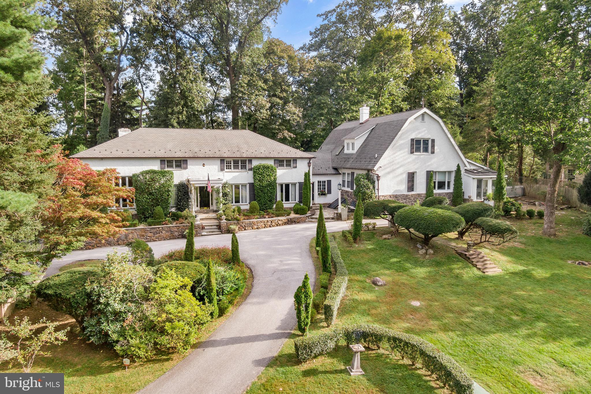 Welcome to “Rockwood”, a one-of-a-kind estate in the heart of Devon’s most prestigious neighborhood. Originally built around 1900, this home was once the former Booth School and Carriage home now combined as one of the main line’s unique estate homes. Featuring 6 beds and 5 full baths with over 6600 sq. ft of interior living space, an attached 3 car garage, and in-ground pool. The 1.4 acre property is located on one of the highest points in Devon which provides sweeping views and seclusion surrounded by the beauty of English landscaped gardens, manicured grounds and iconic barrier privet hedge that transcends all the properties on this exclusive block in Easttown.
Walk up to the front door and admire natural gas lite lanterns giving the glow of yesterday’s stately luxury. Inside there is a welcoming center foyer hallway with staircase and large coat closet, beyond is a first floor office/study. The living room is grand with 11’ soaring ceilings, crown moldings, 9’ tall double-pained windows, fireplace with fruitwood mantle and timeless tiger maple wood floors overlooking the lush front and rear landscape. The dining room features custom built-ins with room to throw lavish dinner parties for 15-20 guests providing an unforgettable dining experience. The gourmet kitchen is bright and sunny with granite countertops, double in wall ovens, Wolf gas cooktop and island workstation. The kitchen is open to a breakfast room with fireplace and hallway spilling into the rear yard and back patio. Beyond is the second family room with built-in bookshelves, a wet bar and cabinetry for refreshments & cocktails after a long day. The family room is completed with another fireplace and mantle with gleaming hardwood flooring and beveled glass featuring all day natural light. From this area find the main bedroom suite features a bright sunroom, large sitting area which overlooks a private garden with private outside door. This primary bedroom suite also features a solarium facing the front on the house with bluestone patio area and stone wall overlooking the pool. The primary suite includes double walk-in closets, an oversized bathroom with double vanity, separate tub & shower. This wing of the home also features another large private bedroom with full hall bath. Back at the main foyer go up the staircase to find three more bedrooms with two full baths (one en-suite bathroom) a playroom, cedar closet and enormous storage attic. The Private Guest House/Apt. offers an outside separate entry and features a Living Room, Full Kitchen/Dining area, 2 bedrooms and a full bathroom with hardwood floors and architectural features throughout, includes a rear second floor deck with large Dutch-door off kitchen, perfect for In-Laws, an Au Pair or “legal” apartment rental at $2,200 per month income.
Updates include, a newer lifetime Slate-Line dimensional asphalt roof with copper accents, new ornamental half round gutters, LED landscape lighting, Haddonstone architectural features, Walpole lighting, updated high efficiency natural gas hot water heaters, septic system installed in 2007, updated boiler in 2016 and regularly serviced HVAC systems. This superior location is within a short walk to the Devon train station, Devon yards, Devon Horse Show grounds, Whole Foods, shopping, restaurants, the Radnor Walking Trail and part of the coveted TE Schools.