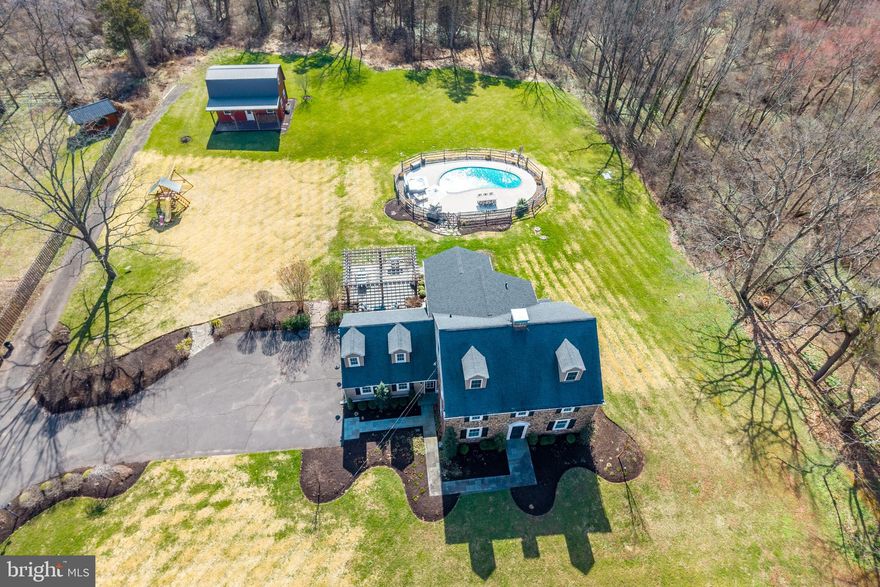 Welcome to 1196 Evansburg Road! Situated on a flat 1.31-acre lot backing to Evansburg State Park on two sides, this stunning stone colonial farmhouse blends timeless charm with thoughtful modern updates while offering a setting that feels both private and connected to everything nearby. From the moment you arrive, a wraparound flagstone walkway and steps lead to two front entrances, while the 2-car garage provides direct access to a functional mudroom complete with a built-in bench—perfect for everyday convenience and organization. The mudroom opens into the heart of the home—an expansive, renovated kitchen designed for both daily living and entertaining. This space features an oversized island with seating, 42" cabinetry with full-extension drawers, extensive granite countertops, GE Café refrigerator and ovens, induction cooktop, farmhouse sink, updated lighting, and a classic brick backsplash that enhances the farmhouse feel. The kitchen flows seamlessly into the dining area and sunken family room, creating an open, inviting layout filled with natural light from walls of windows and a sliding glass door leading to the backyard. The dining area is highlighted by a wood-burning stove and French doors that open to a covered patio, offering an easy transition to outdoor living. A sliding barn door conceals the first-floor laundry and powder room while adding character. Additional main-level spaces include a front living room/den with a second wood-burning stove and a flexible room currently used as a playroom, ideal for a home office, hobby space, or additional living area. A half Dutch door adds another subtle farmhouse detail and charm. Upstairs, the spacious primary suite addition offers over 300 sq ft of comfortable living space with five large windows overlooking the backyard. Features include automated Hunter Douglas blackout shades with central hub, a vaulted ceiling with recessed lighting, and a large walk-in closet with built-in organization and makeup area. The primary bath includes a clawfoot tub, oversized tiled shower with glass door, custom vanity, and auxiliary heat for added comfort. Four additional bedrooms, including one over the garage currently used as an office, a hall bath, and access to an unfinished walk-up attic provide excellent flexibility for future expansion. Step outside to your own private outdoor retreat. Enjoy summer days by the fully renovated saltwater pool or unwind in the hot tub on cooler evenings. Not ready for a swim?  The EP Henry paver patio sits under a pergola and creates a perfect setting for outdoor gatherings, dining, or relaxing while taking in the surrounding landscape. The expansive yard offers plenty of usable space while maintaining a peaceful, open feel.   Tired of relaxing?  Head back into the 2-story detached barn and fire up the golf simulator and challenge your friends to a tee shot on the famed 7th hole at Pebble Beach.  Need to get back into golf shape?  Head to the 2nd floor of the barn and hit the home gym to get you ready for the next round.  Numerous upgrades include newer septic system (2013), replacement windows throughout, CertainTeed siding, 80-gallon water heater, well pump and softener, insulated garage doors, and more. Speaking of the garage, there is currently a suana installed in one of the garage bays and is perfect for recouping after a tough workout in the home gym!  If you don’t want the sauna but need a space to charge an electric vehicle the sauna can be removed and the electric is already installed for a Level 2 home charger.  Not only do you get all this but you are centrally located in the sought after Perkiomen Valley School District and just minutes from all major roads, local employers and all that downtown Skippack has to offer.  We can go on and on about this amazing home but this is one that you have to see in person to truly appreciate all that it has to offer!  Come and check it out today before it is too late!