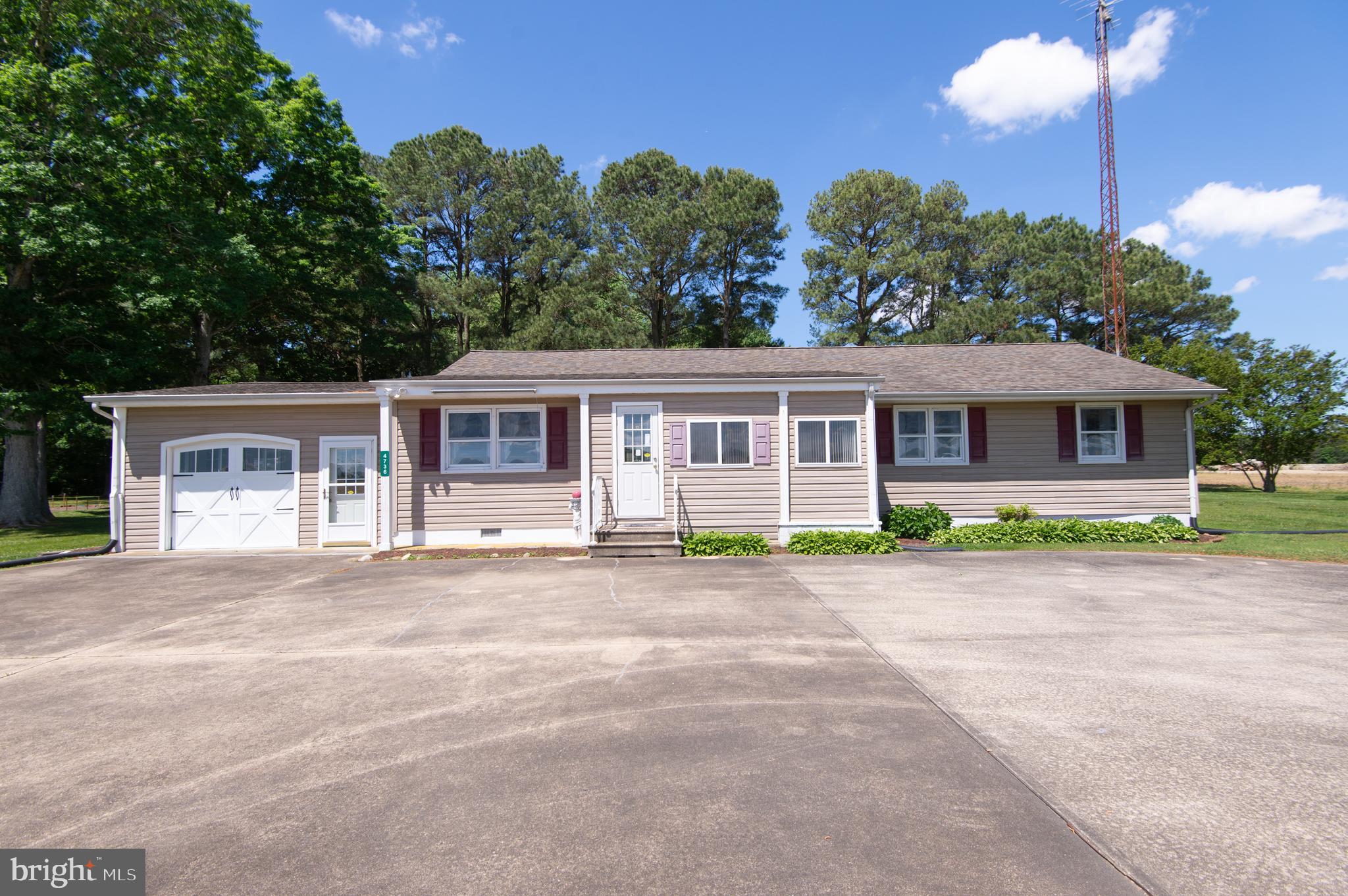 This charming 3-bedroom, 1-bathroom Rancher sits on an acre of land surrounded by farmland and mature trees. A circular driveway provides ample parking and leads to an inviting enclosed front porch. Natural light floods the interior, highlighting the original hardwood floors and spacious layout. The main living area features a bright living room, an open-concept dining room and kitchen, a convenient laundry closet, and a large family room, ideal for gatherings and everyday living. Down the hall, you’ll find three generously sized bedrooms and a full bathroom. From the family room, access the oversized attached garage and step outside to a yard filled with green space, a storage shed, and serene views. This home includes a whole-house gas generator, central air, and a location just outside of the city limits but within close proximity to shopping, restaurants, and commuter routes.