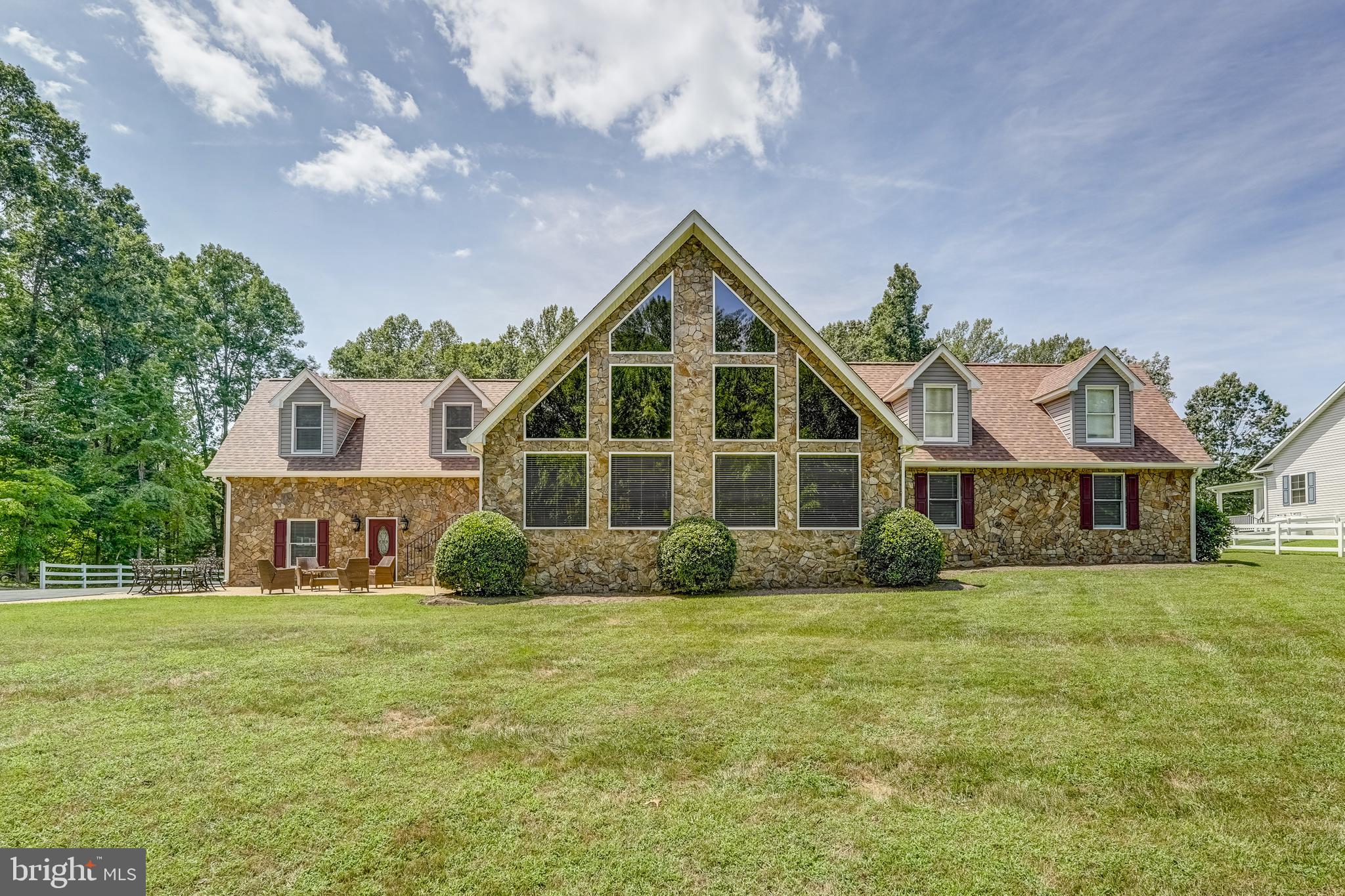 Welcome to your dream retreat at Lake Anna! Nestled in the desirable Sunning Hills subdivision on the public side of the lake, this stunning water-access custom home offers the perfect blend of luxury and relaxed lake living. It includes assigned boat slip #8 in the private community common area, which features easy lake access, a boat ramp, sandy beach, covered picnic pavilion, and more. This spacious 5-bedroom, 3 full and 3 half-bath home is handicap accessible, comes fully furnished, and offers over 3,700 finished square feet of thoughtfully designed living space. The open-concept main level features soaring 22-foot vaulted wood ceilings, a dramatic wall of windows, solid hardwood floors, and a striking stone gas fireplace in the great room. The kitchen is equipped with stainless steel appliances, granite countertops, a breakfast bar with seating, and a wine rack above. Step through the French doors into a massive recreation/family room, complete with a wet bar, floor-to-ceiling stone fireplace, half bath, and a conveying pool table—the ultimate gathering space! The primary suite features a walk-in closet and a fully remodeled, handicap-accessible bath with a roll-in tiled shower, grab bars, soaking tub, ADA-compliant commode, and beautiful finishes. A home office and dedicated laundry room are also located on this wing. Two additional bedrooms and a full bath with a secondary laundry area complete the main level. Upstairs, you'll find two more spacious bedrooms: one with a full bath, the other with a half bath—perfect for guests or extended family. Additional highlights include a finished 2-car attached garage with a half bath and HVAC, plus a massive 40x60 detached, climate-controlled 6-car garage/workshop with heating and air conditioning. The beautifully landscaped 1.47 acre lot features a paved driveway, a covered porch for peaceful mornings, and a spacious back patio ideal for grilling, dining, and entertaining, all designed for low-maintenance enjoyment. Stay connected with high-speed Firefly fiber internet while enjoying the laid-back lake lifestyle. Major upgrades include: New roof (2024) with 6-nail-per-shingle installation and 25-year warranty, New AC and propane furnace (2022). whole-house Generac generator (2020), Wi-Fi thermostats and remodeled primary bathroom. This turn-key Lake Anna property has it all—curb appeal, space, upgrades, storage, and style. Whether you're searching for a full-time residence or an upscale weekend escape, this home checks every box. Come see it for yourself and start living the Lake Anna lifestyle you’ve always dreamed of!