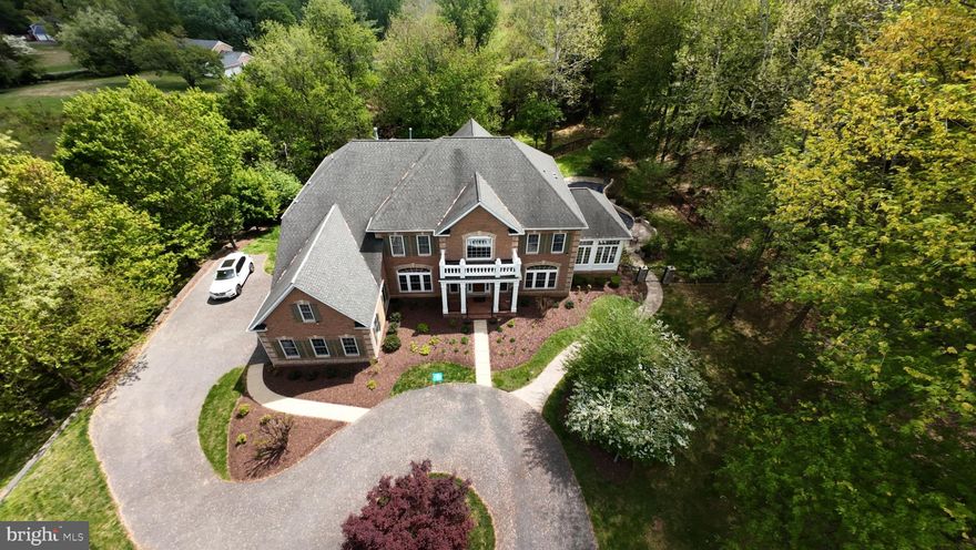 A rare opportunity to own a private estate setting in North Potomac, offering 2.5 acres of space, scale, and architectural presence just minutes from the C&O Canal and within easy reach of Washington, DC.

This custom built residence is defined by grand proportions and timeless design. A stately brick exterior, circular driveway, and mature landscaping create a strong arrival, while hardwood floors, soaring ceilings, and Corinthian columns carry that sense of scale throughout the home.

A two story foyer with dual staircases opens to formal living and dining rooms, while a light filled conservatory provides a quiet, sunlit retreat. The gourmet kitchen features granite countertops, custom cherry cabinetry, high end stainless steel appliances, and a large center island, flowing into a bright morning room with expansive windows overlooking the property.

The two story great room offers a coffered ceiling, a large window, and a gas fireplace with custom built ins, creating a central gathering space. A private library completes the main level.

Upstairs, the primary suite offers a spacious retreat with tray ceiling, sitting area, and a large walk in closet. The primary bath includes a soaking tub, dual vanities, and a glass enclosed shower. Three additional bedrooms each include en suite baths and walk in closets.

The walkout lower level provides flexible living space with a large recreation area, guest suite with a full bath and walk in shower, a second fireplace, wine storage, and additional space for future customization.

Outdoor living includes a pool, gas grill, and a two tier stone patio and deck designed for both relaxation and entertaining.

Convenient access to I 270, River Road, and the Capital Beltway, with shopping, dining, and everyday amenities nearby.