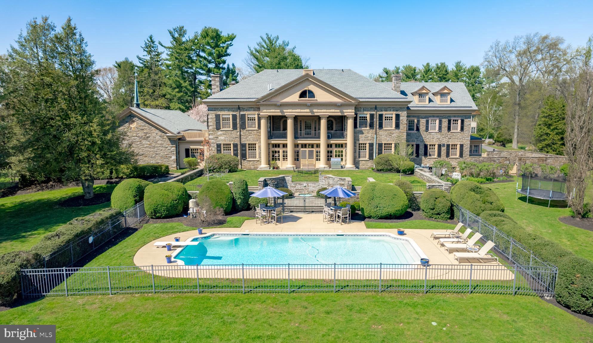 "Windy Hill", an exceptional, classic Georgian-style stone mansion encompassing over 11,000 square feet, was constructed in the late 1920's on one of the highest points in Upper Providence Township, on land that once included the valley now known as Springton Reservoir. Situated on two verdant acres, Windy Hill is ideally located within close proximity to vibrant downtown Media, a convenient 12 miles to Philadelphia and rail lines to NYC and DC, and just 20 minutes to Philadelphia International Airport...This meticulously maintained manor home is replete with stately architectural details - Doric columns, dentilled cornices, Palladian window over the main entrance portico, 24-pane windows, second floor veranda with sweeping views of the rear grounds, all complimented by thoughtful landscape architecture that incorporates an amazing stone gazebo, two fountains. and stone garden walls, patio and pathways. Inside, the grandeur of this home unfolds from the elegant center hall, with French doors leading to a gorgeous sunroom with slate floors, coffered ceiling and egress to the rear grounds and pool. The sunroom can also be accessed via French doors from both the formal dining room and the living room, creating a wonderful, circular flow that connects these generously proportioned, light-filled rooms, and lends itself beautifully to gracious everyday living and large scale entertaining. Both the formal dining room and living room have wood burning fireplaces, as does the family room, which also features a wall of built-in bookcases and egress to the exterior. The kitchen and adjacent butler pantry include a commercial gas range with two ovens, a commercial Miele dishwasher, lots of cabinet storage, along with a large walk-in pantry. This quadrant of the home also includes a cozy breakfast room with a powder room (just off the kitchen) and a 13' x 9' mudroom, with egress to the stone-walled kitchen garden area. There is also a 15' x 11' home office with a charming Dutch door dedicated egress. Rounding out the main level is the chapel wing, which features a 45' x 29' great room with slate floors and cathedral ceiling. This highly flexible mega space has unlimited usages - exercise or artist's studio, music room, recreation room, or potential conversion to garage space for the car enthusiast..... Access the second level via the curved, balconied staircase that leads to the lovely master suite with fireplace, dressing room with built-ins and egress to a private rooftop sun spot, updated master bath, and French doors to the spectacular veranda, an amazing venue from which to view and appreciate the rear grounds. The second level includes three additional generously-sized bedrooms, all with en suite baths, one featuring a fireplace, and one that also accesses the veranda via French doors. Also, a rear hallway on this level leads to a light-filled three bedroom, one full bath au pair / guest suite with back stair....The third level includes a bright and charming bedroom with arched window and en-suite bath. The majority of this level is comprised of a 52' x 24' ballroom with hardwood floors - another amazing and flexible grand space to adapt to your creative endeavors! There are two adjacent game rooms - one with lots of built in shelving - and also a walk-in cedar closet!... For the last thirty years, this incredible home has been lovingly cared for and diligently maintained. Recent infrastructure improvements include roof replacement/copper gutter installation, transition from septic to public sewer, HVAC replacement, hot water heater replacement, full electrical/wiring update, whole house generator and new concrete pool lining. This one of a kind property beckons its next lucky steward and truly must be seen to be fully appreciated.