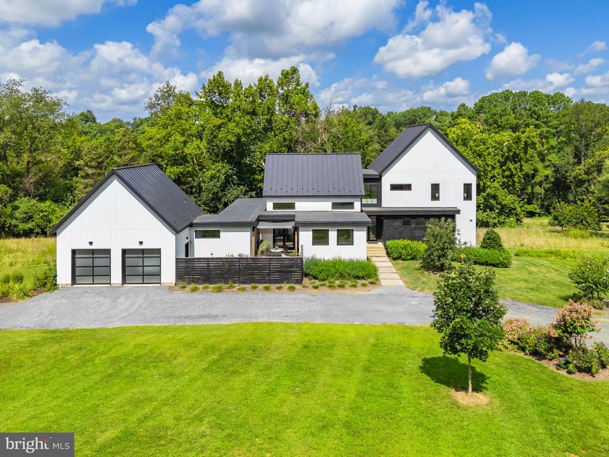 First time offering! This stunning custom-built contemporary home sits on 2+ acres just minutes west of historic Middleburg. Designed and built by an architect for himself, the residence blends cutting-edge technology with traditional stucco, standing seam metal roof and Boral TruExterior siding—crafted from recycled materials for an eco-friendly, low-maintenance finish. With over 4,300 square feet of finished space, the home features 4 bedrooms, including a luxurious main-level primary suite with dual vanities, separate walk-in closets, and a spacious bath. Enter through 8’ glass front doors into a dramatic living room with soaring ceilings, oak floors, and a two-sided gas fireplace that also warms the expansive covered deck. The open floor plan flows seamlessly from living to dining to the gourmet kitchen, outfitted with Carrera marble countertops, a large island, and premium KitchenAid and Jenn-Air appliances. Off the kitchen are the mudroom, laundry room, and access to the two-car garage. A private office and powder room complete this level. Upstairs are two guest suites that share a large bath with dual vanities. Built-in bunk beds and a cozy sitting area make the landing a perfect retreat. The walk-out lower level offers a large recreation room, kitchenette, game room, storage, and an additional bedroom with full bath. Step outside to the firepit beneath custom grid shade sails. Outdoor living shines here with a Trex deck designed for both dining and lounging, a covered sitting area opening to a private garden with raised beds, and mature landscaping by Robert Ferguson (Scotland) and John Magee (local). Rewilded areas support natural habitat, while a charming block garden shed—once a two-stall barn—adds character. In the heart of horse and wine country, yet only 40 minutes to Dulles Airport and an hour to Washington, D.C., this turnkey property offers privacy, sustainability, and sophistication. Don’t miss this rare offering—it won’t last!