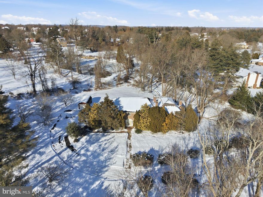 Step inside a truly one-of-a-kind Makefield Chase estate where timeless craftsmanship meets dramatic architectural design. This impressive 4-sided brick colonial offers 5 bedrooms, 4.5 bathrooms, multiple fireplaces, a 3-car attached garage plus 1-car detached garage, and sits proudly on a spacious 2.5 acre home site surrounded by mature landscaping. A grand entrance welcomes you through double front doors into a stunning two-story foyer highlighted by a curved staircase, designer tile flooring, rich wood detailing, crown molding, chair rail accents, recessed lighting, and elegant arched entryways that set the tone throughout the home. Entertain with ease in the formal dining room featuring double French doors, a wood-burning fireplace, bay window, and classic molding details, with convenient access to the kitchen. The living room continues the charm with hardwood floors, built-in bookshelves, recessed lighting, and another cozy fireplace. The showstopper of the home is the breathtaking two-story conservatory/library addition — a space straight out of a storybook. This extraordinary room features floor-to-ceiling custom bookshelves, hardwood flooring, a spiral staircase, wood-burning fireplace, ceiling fan, and a full bathroom. Upstairs, discover wall-to-wall shelving and a stunning stained-glass coffered ceiling, creating a dramatic and unforgettable architectural focal point rarely found in today’s homes. The kitchen offers an island, breakfast nook, bay window, tile backsplash, and designer tile flooring, flowing seamlessly into the family room with stone-front fireplace with oversized firebox, wet bar, recessed lighting, and sliding doors leading to the sunroom — perfect for everyday living and entertaining alike. The main level is complete with a laundry room, powder room, and a private main-floor in-law suite with full bath and outside access, providing ideal flexibility for guests, extended living, or home office space. Upstairs, the primary suite is a retreat of its own with a sitting area, built-in bookshelves, wood-burning fireplace, en-suite bath, 2 walk-in closets, skylights, and separate dressing area. Three additional generously sized bedrooms share a hall bath with dual bowl sinks, while a finished walk-in attic provides excellent additional storage. Located in the highly sought-after Pennsbury School District, this home offers a rare combination of space, architectural character, and opportunity to personalize and modernize while preserving its exceptional craftsmanship and charm. A remarkable property with endless potential.  This is not just a home, it’s an experience.