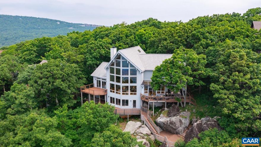 This stunning property is a true gem nestled within the picturesque Wintergreen community. With its breathtaking views and elegant design, this home offers an unparalleled living experience. Prepare to be captivated by the panoramic views of the Blue Ridge Mountains that surround this property. Step inside to discover a thoughtfully designed floor plan with an open concept that creates a seamless flow. The view envelops you from the front door, with the floor to ceiling windows in the living room along with the gorgeous stone fireplace. The kitchen offers granite counters, lovely glass cabinetry, ample storage, and a solarium breakfast area. The primary suite is on the first floor, with a walk-in closet and large bath. Another bedroom, full bath, dining room and laundry space is also on the main floor. 3 bedrooms are upstairs, one with its own attached full bath. The loft area is perfect for a home office or relaxing while not missing the view. A game room is in the basement, boasting its own Blue Ridge boulder and a bonus room with a convenient half bath. 2 car garage, new Trex decking and railings (except for lowest tier), paved driveway and new exterior lights. Easy access to Wintergreen shopping, restaurants, and skiing.