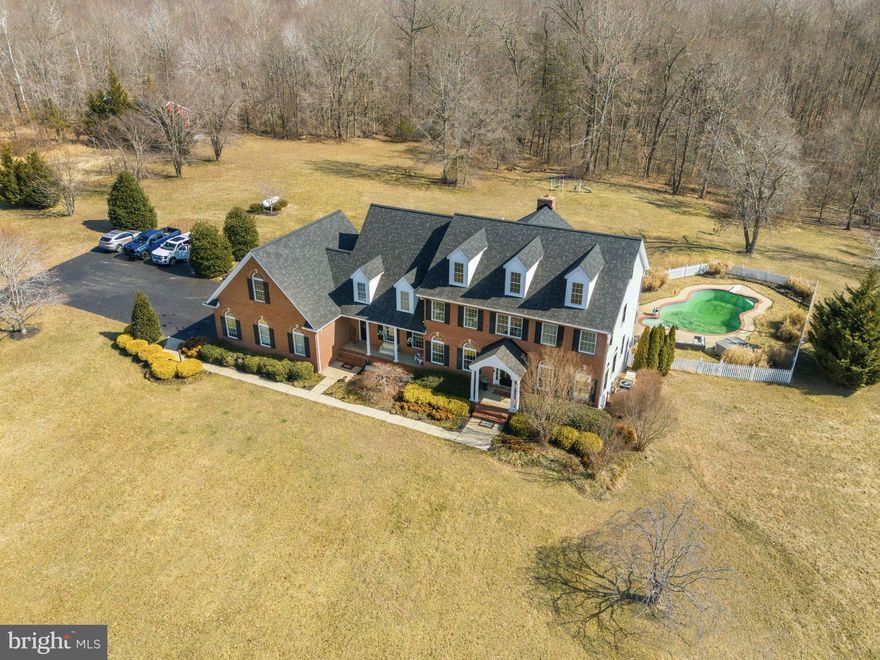 Lined with mature trees and backing to a peaceful stream, this stunning home offers the perfect blend of luxury, comfort, and everyday livability across 7 beautiful private acres. The setting feels like a private retreat, yet it’s still conveniently located for commuting with easy access to major routes. From the moment you arrive, the home makes an impression with its stately presence, two front entrances, and oversized three-car garage with storage above. Inside, you’ll find timeless details throughout, including wainscoting, crown molding, custom built-ins, and detailed woodwork that add warmth and character without feeling overdone. The main level is designed to make daily life easy while still feeling special enough for entertaining. The formal living and dining rooms are perfect for gatherings, while the enormous family room creates a comfortable place to relax, featuring both a fireplace and a pellet stove. The gourmet kitchen is truly the heart of the home, offering a large workspace, quality appliances, and an insta-hot faucet for added convenience. Just off the kitchen, the bright breakfast room and rear deck provide the perfect spots to enjoy morning coffee while taking in views of the trees and surrounding acreage. There’s also a first-floor office that could easily serve as a main-level bedroom if needed, along with a spacious laundry room featuring extra cabinetry, washer, dryer, and a laundry tub. Upstairs, each of the four bedrooms feels like its own private retreat, all featuring en-suite baths and great storage. The primary suite stands out with its huge sitting area, spa-style bath with soaking tub and separate shower, and incredible closet space designed to hold everything with room to spare. The mostly finished basement adds even more living and entertaining space with a large recreation room, entertaining area, and a cozy wood-burning stove with a classic brick hearth and mantle. Walk-out access leads directly to the backyard and pool area, making indoor-outdoor living feel seamless. There’s also an unfinished exercise space, tons of storage, and a rough-in for a future bathroom. Outside is where this property truly shines. The gunite pool creates a resort-like feel during the warmer months, and the hot tub is included as-is. The detached 30x40 barn-style building with concrete flooring offers endless possibilities for a workshop, hobby space, or storage. The partially wooded acreage offers privacy, natural beauty, and ample space for horses, if desired. Additional features include a water filtration system and a Generac generator hook-up already in place and being wired. Located in a small subdivision with no HOA, this property offers the freedom and space that’s becoming harder to find.This is the kind of home where everyday living feels a little more special, where entertaining is easy, and where years of memories are waiting to be made. A truly beautiful property inside and out.
** Senior pets on premises. They will be in the garage for initial showings, but can be removed for 2nd showings & inspections