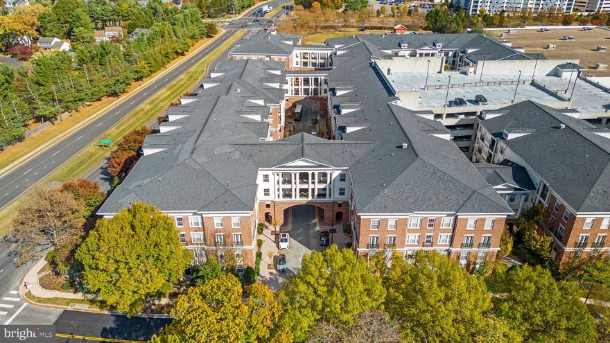Welcome to this lovingly cared for  3-bedroom, 2-bathroom condominium in the prestigious Kentlands Colonnade. This highly sought-after floor plan boasts a spacious, light-filled interior, accentuated by elegant arched doorways and hand-scraped hardwood floors. The expansive living area, complete with a formal dining room and a cozy gas fireplace in the living area, creates an inviting ambiance for relaxation and entertaining. The gourmet kitchen features quartz countertops, stainless steel appliances, and a stylish tile backsplash. Retreat to the luxurious primary suite, where you'll find access to the balcony and a spa-like ensuite bathroom with  a large walk-in tiled shower, and dual vanities as well as a large walk-in closet.  The additional two bedrooms boast large closets and windows and share a fully updated bath with double vanity, and tiled surround tub/shower.  There is a full laundry area on this wing as well. Residents of this secure building enjoy access to a host of amenities, including a sparkling pool, several party, game and wine rooms, and a state-of-the-art fitness center. This condo also includes 2 parking spaces in the garage located across the street from the condo. Nestled on the edge of Kentlands, this exceptional residence offers unparalleled convenience to a vibrant array of shopping, dining, and entertainment destinations in Kentlands.  With its blend of sophistication, comfort, and convenience, this remarkable condominium presents an extraordinary opportunity to experience the very best of upscale living.