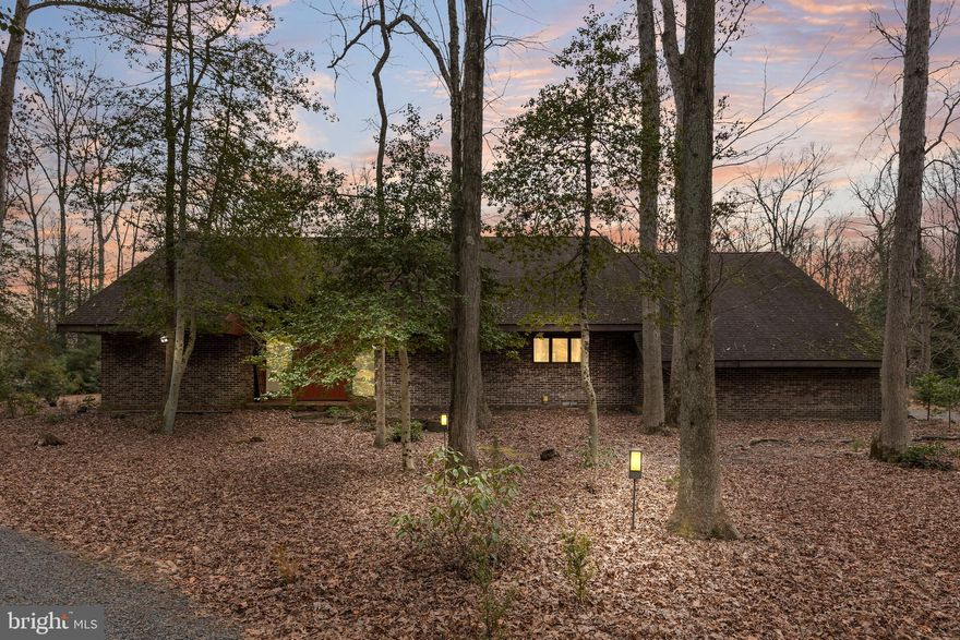 You have found your retreat away from it all at 143 Ridge Road! Follow the picturesque winding driveway through the woods to a private wooden oasis. As the driveway curves around, you’ll notice this unique home come into view. Enter through the inviting custom wooden doors, which are framed in windows for plenty of natural light in the beautiful foyer. Notice the gorgeous wooden walls, the unique tile, and mid-century open air stairs and chandelier with a second floor balcony walkway. The foyer opens to the bright living area and dining area. The first thing you’ll notice is the wall of windows connecting you to nature. The unique sunken living area features a raised brick fireplace and two sets of sliding doors for easy access to the backyard and combines the two spaces together. The den/office is tucked away behind french doors and features wall to wall shelves which creates a classic office space. In the dining area, enjoy the gorgeous wall of windows, opening the space to nature and a  view of the backyard. A unique highlight to the dining room is the indoor patio which can be used for plants or other featured items. There’s a serving window for easy access to the kitchen and making entertaining simple. Enter the beautiful kitchen with plenty of cabinets so that you won’t run out of storage. Enjoy the peninsula with built in range and bar seating, built in corner oven, wood stove and quaint breakfast area. This home continues to help you to enjoy nature with the sliding doors in the kitchen to the backyard. There's an unfinished bonus room with two story ceilings and plenty of room to make it your own. Finishing the first floor is the mud room/laundry room, powder room, storage area and 2 car garage. Follow the beautiful wooden stairs to the second floor and cross the balcony to the main bedroom. Notice the unassuming walk in closet that is the length of one wall and the main bathroom that is waiting for your personal touches. There is a large second bedroom, a third bedroom, a full bath and finishing the second floor is another extra room that is being used as an office. Outside there are pathways with beautiful trees and plants with the special feature of a koi pond. Make this hidden treasure yours today!