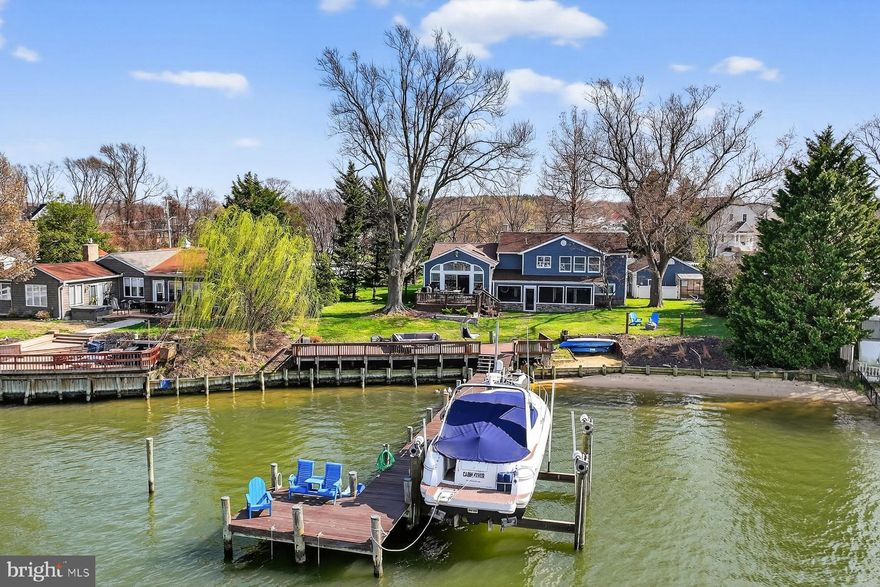 Ideally situated on Back Creek/Bodkin Creek with easy access to the Chesapeake Bay, this beautifully reimagined home captures the essence of waterfront living. Recently renovated from top to bottom, it has been thoughtfully updated with a refined, modern aesthetic while preserving its inviting coastal character.
Positioned to maximize its’ setting, the home offers sweeping views across Back Creek from nearly every living space. The main level unfolds with a seamless connection between the kitchen, dining, and living areas, anchored by expansive windows and soaring ceilings that draw in natural light and frame the water beyond. The gorgeous kitchen includes soapstone, quartz, and a live-edge wood countertop and stainless-steel appliances. The chef will be thrilled with the size of the island for meal prep! The waterside family room, with pellet stove, has a vaulted ceiling and wall of glass. Just outside, a spacious waterfront deck becomes a natural extension of the home.
The upper level features three well-proportioned bedrooms, including a private primary suite with tranquil water views, a walk-in closet, and a spa-like ensuite bath complete with a soaking tub. The walk-out, lower level provides additional flexible living space, perfect for a media room, guest overflow, or casual gathering area. A standout feature of the home is the expansive screened porch with space for dining, lounging, and unwinding in the hot tub, all with easy access to the backyard.
Along the shoreline, the property is equally compelling. A private sandy beach and a substantial waterfront deck set the stage for long summer days on the water. The deep-water pier is outfitted with multiple slips, a 40,000 lb lift, and a jet ski lift, ready to accommodate a range of boating lifestyles. Thoughtful details, from a place for your hammock at the water’s edge to a dedicated fire pit area, complete the experience. There is a one-car garage, ample storage in the adjoining structure, and plenty of parking available in the driveway.
This turnkey waterfront opportunity is located in one of the most desirable boating locations and offers immediate enjoyment to all the Bay has to offer. Explore various nearby creeks, with waterfront restaurants, or spend the day fishing on the Bay. By car, it’s an easy commute to Baltimore, Annapolis and DC.