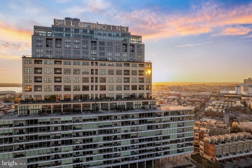 Experience elevated waterfront living in this exceptional one-level residence at Silo Point, where dramatic architecture meets refined design. This stunning two-bedroom, two-and-a-half-bath condominium boasts 1,860 square feet of expansive, light-filled living space highlighted by sweeping city views and direct waterfront vistas. Floor-to-ceiling windows and soaring 10+ foot ceilings fill the home with natural light, while rich hardwood floors, custom built-ins, and designer lighting create a sophisticated and welcoming atmosphere. The beautifully renovated gourmet kitchen features quartz countertops, a custom glass backsplash, and stainless steel appliances, seamlessly blending style and functionality for everyday living and entertaining. The thoughtfully designed layout includes a spacious powder room and a versatile guest suite complete with a custom Murphy bed and built-in bookcase, along with a private ensuite bath featuring a marble vanity. The primary suite offers a peaceful retreat with a comfortable sitting area, an expansive custom walk-in closet, and a spa-inspired bath with double vanity, soaking tub, and separate shower. Step outside to the private balcony to enjoy tranquil eastern exposures and spectacular morning sunrises over the water. Modern conveniences include Lutron motorized blinds, Nest thermostats, and two secure assigned parking spaces. Residents enjoy a full-service lifestyle with a 24-hour concierge, on-site management, state-of-the-art fitness center with yoga studio and treatment room, game room, boardroom, and the spectacular 19th-floor Sky Lounge offering panoramic harbor and city views. Originally built as a 1920s grain elevator and transformed into one of Baltimore’s most iconic waterfront residences, Silo Point offers a rare combination of architectural distinction, amenities, and vibrant urban living. Located in the desirable Locust Point neighborhood, Silo Point offers excellent accessibility with quick connections to I-95, making commuting simple and efficient. The community is ideally positioned near the Baltimore Peninsula, Fort McHenry, Latrobe Park with easy access to downtown Baltimore and the Inner Harbor. Residents enjoy close proximity to local restaurants, parks, and waterfront attractions, while BWI Airport and Washington, DC are both conveniently reachable for work or travel.