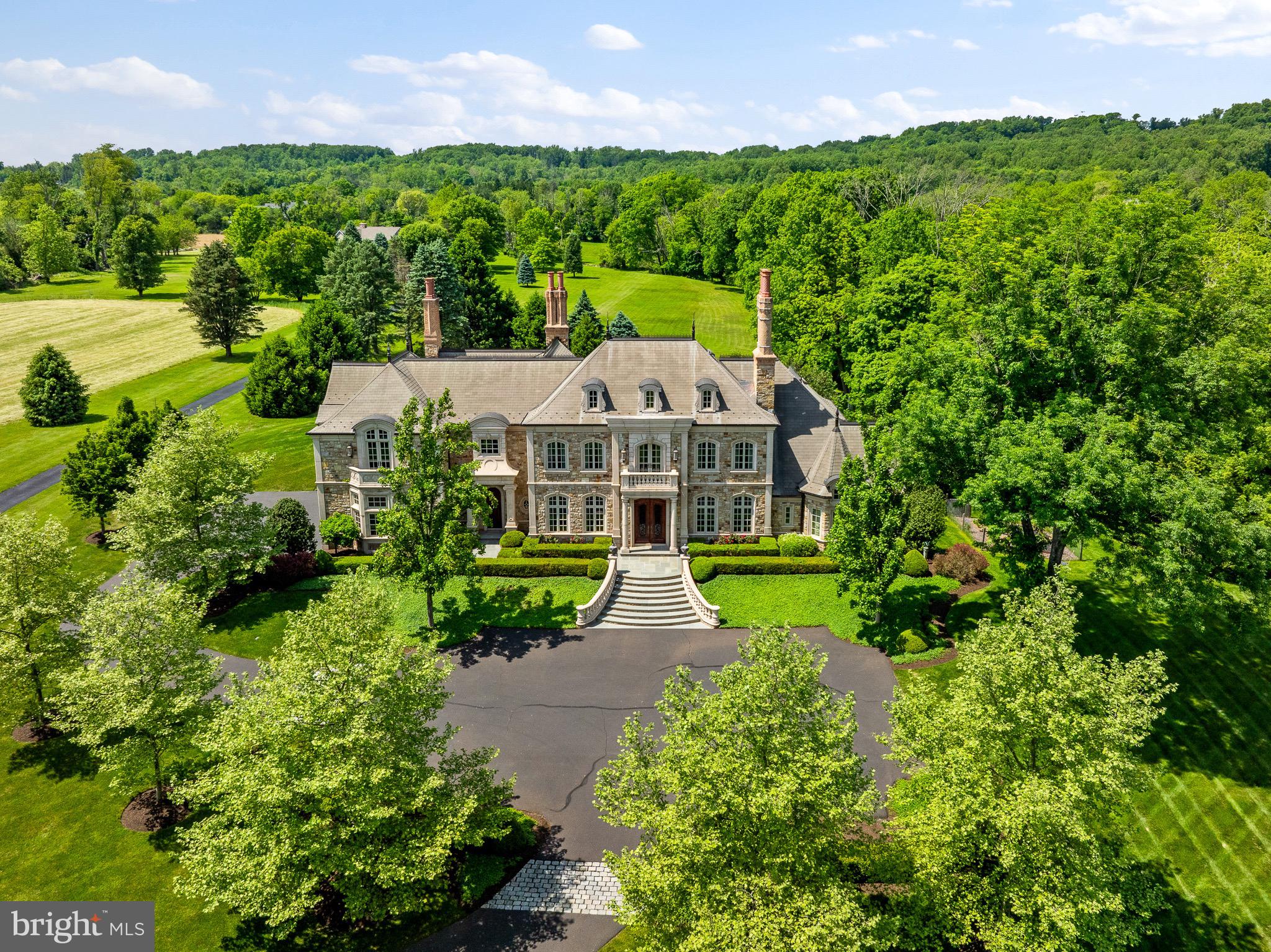 Indulge in the epitome of opulence with the award-winning Château, an awe-inspiring 10,000 square foot, two-story residence nestled in the heart of Buck's County. The award-winning Château, part of World's Best projects, received commendation in The International Property Awards 20th Anniversary issue. This French-styled, all hand-cut stone home stands as a testament to architectural excellence and sophistication. Renowned for its award-winning design, this French-style stone haven seamlessly blends old-world charm with modern luxury, featuring hardwood and marble floors, and two stunning limestone staircases adorned with custom-made brass iron railings. With ceiling heights soaring at 22 feet or more, adorned with intricate luxury crown moldings and decadent arches, The Château seamlessly blends old-world charm with modern elegance. This 4-bedroom, 4.5-bathroom masterpiece presents a main-level primary suite that redefines opulence. The primary bathroom in this suite is a luxurious sanctuary, boasting a bird's-eye ceiling, custom cabinetry, a hand custom sculpted marble tub, and a marble shower. The heart of this residence is the chef's kitchen, a culinary haven with handcrafted solid wood cabinetry. Additional grand spaces include a formal parlour, an elegant dining room, and a conservatory with glass, steel doors that open off the grand hallway, creating an inviting flow of space. Throughout the home, fireplaces with intricate designs serve as focal points, adding warmth and sophistication. Equally impressive is the exterior, showcasing a 65-foot fireplace crafted from stone, brick and bluestone, adorned with a decorative fleur-de-lis design, creating a captivating focal point that adds both charm and warmth to your outdoor haven. Outside, The Château beckons with an in-ground saltwater heated pool, surrounded by meticulously landscaped gardens. It's an idyllic setting for year-round enjoyment and entertaining. This is not just a home; it's a masterpiece waiting to be experienced.