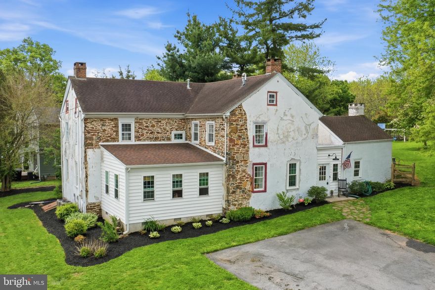 Step into timeless charm and modern comfort in this beautifully preserved sandstone home dating back to the 1760s. Rich in character and thoughtfully updated, this one-of-a-kind property blends historic craftsmanship with tasteful 2020 renovations designed to maintain the home’s original integrity.
Inside, you’ll find stunning exposed wood beams, deep window sills, original wood flooring on the second floor, and a warm living room centered around a striking stone fireplace with a handcrafted wooden mantle. The custom kitchen is a true showpiece, featuring handmade cabinetry, butcher block countertops, a classic farmhouse sink, and charming wainscoting details in the breakfast nook and backsplash. The spacious layout offers four upstairs bedrooms in the main house, along with a full bath upstairs and an additional full bath on the main level. The former summer kitchen has been thoughtfully converted into a private office space with an additional upstairs bedroom—ideal for guests, remote work, or flexible living arrangements.  Set on 0.69 acres, the property features a large fenced backyard perfect for entertaining, gardening, or play, as well as a private patio just off the kitchen for quiet mornings or evening gatherings. A walk-up attic provides exciting potential for future expansion or additional living space. This extraordinary home offers the rare opportunity to own a piece of history without sacrificing the comforts of modern living.