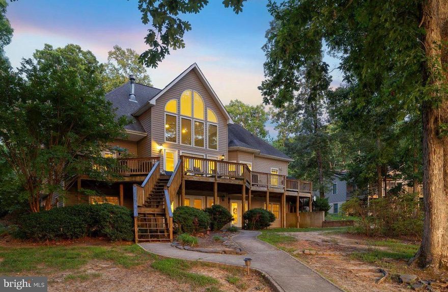 This waterfront masterpiece elegantly graces Lake Anna's public side; set on over 100 feet of peaceful shoreline, this part of Lake Anna offers the cleanest and deepest water.   Now a high-functioning short term rental, this NON-HOA, fully-furnished, three-level retreat offers breathtaking water views, high-speed internet via Xfinity, unmatched amenities, and incredible short-term rental potential for investors.  Whether you're looking for your dream lakefront getaway or a high-performing investment property, this home delivers on both fronts.  Perfectly situated in a private quiet wide cove, this 4,800 square ft 6 bedroom turn-key retreat offers extensive bulkheaded shoreline on one of the lake’s most scenic, wide-open stretches.  Guests and owners alike will love the clean swimmable water, massive two-slip boathouse with tiki bar, large relaxing fire pit, and private sandy beach — everything you need for unforgettable lake days.  The high vaulted ceilings of the main floor greet with a quiet elegance, while the floor-to-ceiling windows showcase your priceless views of Lake Anna, and saturate the open main level with natural sunlight.  An oversized fireplace with mantle anchors the great room, which transitions seamlessly into the wide open kitchen with stainless steel appliances, granite counters, and a spacious island perfect for entertaining.  The first-floor primary bedroom suite is a luxurious and spacious retreat, complete with French doors leading out to the deck, radiant heat flooring, jetted tub, large walk-in shower, dual vanities, and a spacious walk-in closet. The first floor also offers a private office, separate dining room, and laundry room.  Upstairs, your family and guests will enjoy two additional bedrooms, a full bath, and a balcony overlooking the great room and lake.  The massive walkout basement offers yet another lakeside bedroom suite with bathroom, two additional guest bedrooms, a full bath, ping pong table, built-in shelving, dry bar, and second fireplace — ideal for accommodating large groups or multiple families.   A pavered path meanders down to the water's edge, at which you'll find a peaceful fire pit, private sandy beach, and a large boathouse with two slips, electric boat lifts, tiki bar with tile countertops, and bench swing perfect for enjoying sunsets and hot summer nights.  If you're an investor, this home is tailor-made for short-term rental success, with a versatile layout that sleeps many guests, sprawling indoor and outdoor living spaces, a recreation basement, and perfect waterfront area that makes it a top choice for vacationers.   Home also includes tankless hot water heater, central vacuum system, intercom and security systems, and storage sheds.   Premiere location on Lake Anna's public side, toward the eastern end of the lake, where the water is the most clear and most deep.  Rental history available in the documents section; home comes fully furnished.