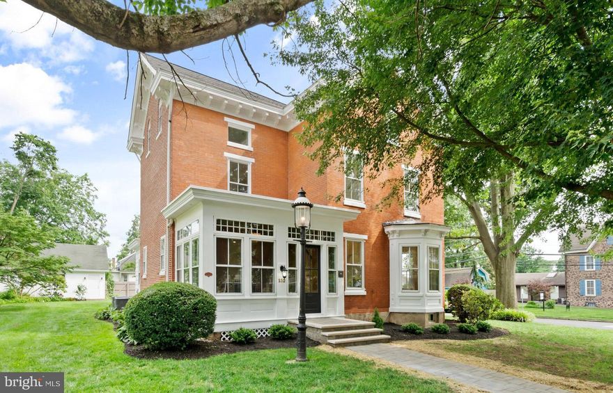 Welcome home to the William Vaux House at 132 West Oakland Avenue in Doylestown Borough. Experience refined luxury in this exceptional architectural jewel, where the elegance of 19th-century design harmoniously blends with the finest modern amenities. Nestled along one of Doylestown Borough’s most coveted streets, this distinguished residence occupies one of the most desirable lots in town, offering 2,747 square feet of meticulously curated living space across three levels. Originally built in 1875, this 4-bedroom, 3.1-bath brick manor has been exquisitely restored, including a full masonry repointing that showcases the craftsmanship of a bygone era. A canopy of mature trees provides natural privacy as you approach the new walkway leading to the enclosed, all-season front porch—an inviting prelude to the sophistication found within. Inside, the foyer opens to expansive entertaining spaces adorned with newly installed wide-plank hardwood flooring, 9-foot ceilings, recessed lighting, and thoughtful architectural details throughout. The chef’s kitchen is a sunlit sanctuary featuring custom hardwood cabinetry, quartz countertops, a neutral tile backsplash, and premium appliances, including a Bosch gas range. The kitchen flows effortlessly into the living room, where natural light streams through antique glass windows, preserving the home’s historic character while embracing contemporary comfort. Celebrate special occasions in the elegant formal dining room, enriched by a charming bay window. At the rear of the main level, enjoy morning coffee on the intimate back porch overlooking the gardens. A stylish powder room and convenient laundry room complete this floor. Step outside to a brand-new paver patio, ideal for alfresco entertaining, which leads across the manicured lawn to the detached two-car garage—equipped with its own subpanel and ample storage. Ascend the original staircase to the tranquil primary suite, featuring a generous walk-in closet and a spa-like en suite bathroom with tiled stall shower and dual vanity. Wide plank hardwood floors extend through the second bedroom, which also offers an en suite bathroom. The third floor boasts two additional bedrooms with plush new carpeting and abundant closet space. These bedrooms share the third full bathroom with bathtub shower and dual vanity, all with panoramic views of sunrise and sunset over Doylestown’s rolling hills. A bonus room (possible fifth bedroom) offers additional space on the third floor. The lower level is awaiting your recreational use, for fitness, hobbies, or ping-pong, with plenty of room for storage. It's been freshly updated with new paint and a suite of modern mechanicals, including a new 200-amp electrical panel, natural gas conversion, new sewer lateral, high-efficiency HVAC, a 75-gallon water heater, and new plumbing—ensuring long-term peace of mind. Set along the celebrated route of the Bucks County Classic bike tour, this home places you within walking distance of the Doylestown Arts Festival, Concerts at the Commons, Hollywood Summer Nights at the County Theater, and the town’s vibrant mix of boutiques, restaurants, and cultural venues. Schedule your private showing of this spectacular property, where history meets modern luxury, and every detail invites you home!