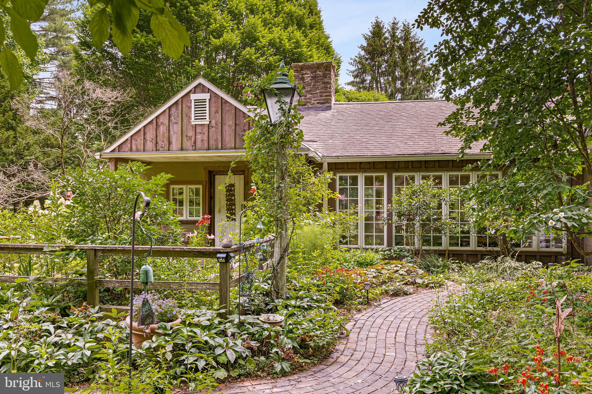 Cloudhill, currently an art collector’s retreat, is a dramatic, light-filled 4-5 bedroom 5 bath country estate in a serene and private setting near Brandywine Valley’s famous Longwood Gardens and Winterthur. Its 4.5 acres of native and specimen plantings, meadow, and woodlands include its own path into an extensive adjacent trail system covering nearly 400+ acres of conserved public open space. Just minutes away from first-class Brandywine Valley shopping, restaurants, recreation, and schools, this property is an easy commute to both Wilmington, DE (including Amtrak), and West Chester, PA, and convenient to Philadelphia and Baltimore. The main house has fine architectural details such as wood-beamed cathedral ceilings, extensive hand-forged ironwork, 3 working traditional brick Rumford fireplaces, and a wall of windows with garden views in every room. Custom finishes include reclaimed wooden barn beams, wide plank pine and walnut flooring, curved walls and ceilings, and custom floor-to-ceiling tiger maple library shelving. In addition, every room on the main floor offers access to at least one of three lovely stone and brick patios, each leading to its own picturesque garden. Garden areas include a shady courtyard with native trees, a kitchen garden with raised beds and herbs, and a sunny Mediterranean stone-terraced garden. Inside, the antique-filled gourmet kitchen, which features a commercial stove and grill adjacent to a large circular zinc countertop, opens to the expansive living, dining, and family rooms offering over 2500 sqft of entertainment space. The private upstairs master suite includes an oversized bath and steam shower, plus two walk-in closets. In a separate upstairs wing, two guest suites, each with its own bathroom, look out on gardens, woods, and meadows. An additional downstairs master suite with its own adjacent patio is currently used as an art studio and office. Outbuildings include an oversized 3-car detached garage and a large shop/storage barn readily convertible to a private guest house. Additionally, the property has a full-power backup system plus a new septic system. Designed and built with ecological considerations in mind, the house combines extensively repurposed materials, a geothermal HVAC system, and a recently planted permaculture food forest. These are just a few examples of the many distinctive features that distinguish this charmingly understated Chester County home.