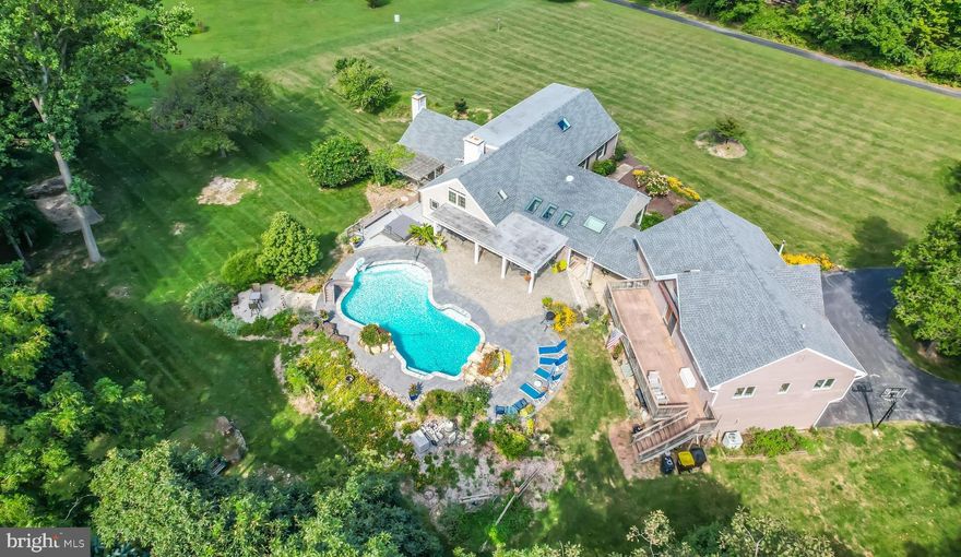 Welcome to your private oasis! Backing directly to over 126 acres of protected conservancy land in Willisbrook Preserve, you'll enjoy peaceful, uninterrupted natural views. This beautifully crafted custom home is nestled on 2 acres of serene, landscaped grounds bursting with vibrant, mature flowers and features a sparkling salt water pool and hot tub.

Step inside through a sun-drenched breezeway lined with floor-to-ceiling windows and skylights, framing stunning views of the backyard and pool. The breezeway opens to the beautifully designed kitchen, featuring vaulted ceilings with skylights that add a warm, open feel. It flows into a spacious great room with exposed beams, floor-to-ceiling windows, ceiling fans, and a striking stone fireplace. A built-in bar with wine fridge completes the space, ideal for hosting. Through the foyer you find a formal living and dining room with a fireplace and ample space to host large family gatherings. Completing the first floor are two bedrooms - one with a bathroom suite – laundry room, two half baths and an office. 

Upstairs, the primary suite offers hardwood floors, two closets, and an updated full bathroom that is also accessible from the hall. A sunny hallway with custom built-in storage leads to a spacious 4th bedroom.

The lower level features a partially finished basement that is perfect space for a home gym or additional living space. 

Located above the attached 3-car garage is a full in-law or guest suite with its own private entrance that includes a chair lift. This thoughtfully designed space features an open-concept living area with a fully equipped kitchen, laundry, half bath, and two bedrooms — one of which includes a private full bath. A large deck off the suite overlooks the pool, gardens and protected conservancy grounds.

Don’t miss the opportunity to own this truly special property — where nature, comfort, and craftsmanship come together nestled in a convenient location within the award winning Great Valley School District.