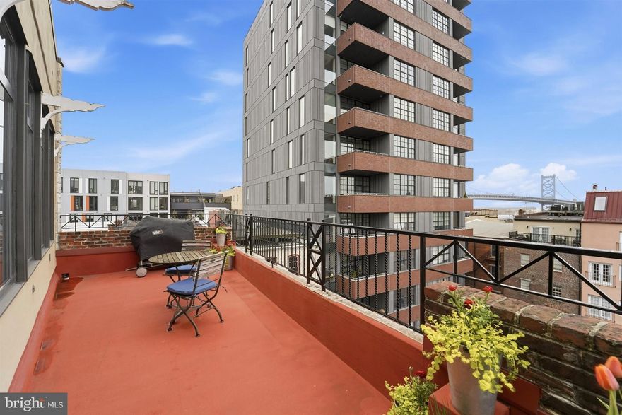 Be a part of Old City-- an unmatched urban experience where culture, convenience, and character converge.  Nestled within the history and culture of this vibrant neighborhood is The Chocolate Factory, an iconic condo conversion situated on cobblestone streets within walking distance of galleries, acclaimed dining, boutiques and treasured landmarks.   This exceptional bi-level penthouse with 12’ ceilings throughout delivers a sophisticated take on city living, distinguished by its scale, premiere location, and a sweeping view of both Philadelphia’s most historic neighborhood as well as the iconic Ben Franklin Bridge and Delaware River.  A dedicated off-street parking spot behind a gated entrance provides convenience and security.  You’ll ascend to the penthouse by elevator which opens directly into the atrium foyer of the 1st level via an ornate custom door with gold leaf inlay glass.   Here, you will find two large bedrooms, each enhanced with custom doors and hardware.   To the right is the primary suite, facing east with bridge views.   This large bedroom with wall-to-wall carpeting provides plenty of storage, a built-in bookshelf, a walk-in closet as well as the laundry room, a small balcony and access to the full bath.   The modern bath is appointed with a double basin vanity, two medicine cabinets, a luxury soaking tub and oversized stall shower.   Bedroom 2 is currently styled as a den/office.   Rich Brazilian Cherry hardwood flooring, a gas fireplace, custom built-in shelving, and a wall of southwest-facing windows create a warm and inviting space. Two walk-in closets and a small balcony further enhance this room’s appeal while a Sonos sound system seamlessly integrates tv and music here. Ascending to the 2nd level, you’ll notice the dramatic two-story exposed brick wall and a custom ironwork banister created to reflect the arches of the Ben Franklin Bridge.  The hallmark of the 2nd level is the open floorplan that nods to loft-style living but provides refined finishes able to accommodate any style of furnishings.   Brazilian Cherry hardwood graces the floors throughout this level and a wall of windows with a French door opens to a large and wide balcony,  immediately catching your attention.   This east facing outdoor living space is a sought-after amenity, particularly with its bridge view and perspective on Old City’s architecture.   This 2nd level provides ample LR and DR space and a kitchen ideal for entertaining or simply sipping coffee and enjoying the city view.  Offering gas cooking, stainless appliances, a built-in microwave, disposal, plus plentiful cabinet and counter space the kitchen is as functional as it is dramatic.  A standout feature is the oversized powder room, where reclaimed cross-cut wood flooring—sourced from historic Philadelphia structures—has been repurposed into striking tilework, offering a subtle nod to the building’s rich heritage. Notably, this space was originally configured as a full bath, and existing plumbing remains, presenting an opportunity for future conversion.  Convenient to commuter roadways and public transportation.  Note- for added peace of mind, any fogged windows will be replaced this spring.  Dogs and cats permitted
