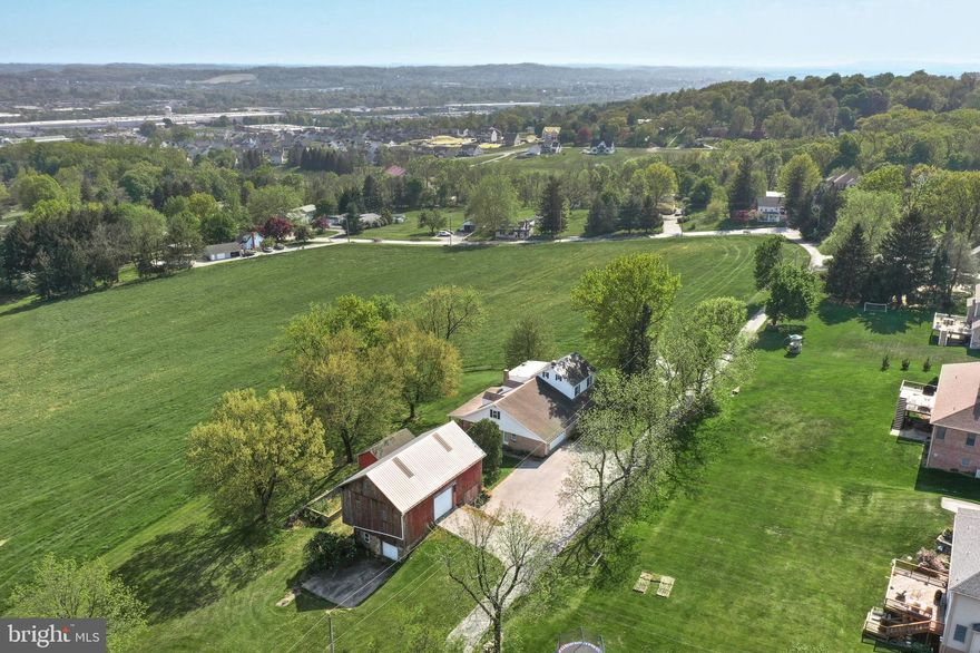 Thirteen acre farmette with stunning countryside valley view located in Springettsbury Township, York County, PA. The approximate 3,060 square foot five-bedroom Old Colonial style house with original 60’s décor includes a mid-size 50’ X 24’ bank barn circa 1853 with hayloft, three potential horse stalls, newer aluminum roof and gutters and downspouts, 24’ X 16’ hog pen and 30’ X 14’ chicken coop outbuilding. The spacious kitchen was renovated in 2013 with granite countertops, tile backsplash and wood cabinets and leads out to a large masonry covered patio where you can relax and relish the terrific views of woodlands, open fields, and the valley below. Main floor has dining room with hardwood floors, living room with fireplace (decorative only), two bedrooms with closets and a full bath with tub shower with access to the main floor laundry/mud room, an oversized two car garage with access from the living quarters and patio. The second floor offers three bedrooms all with closets, and a full bath with tub shower and double sinks. The unfinished large and roomy attic is ideal for lots of additional storage or more living space with generous ceiling height. The substantial unfinished basement offers a huge recreation room with a large fireplace  (nonfunctioning) and walk out patio to enjoy the incredible valley view. Basement has an authentic walk-in fireplace, old coal bin, well with UV system and water neutralizer, Rheem central air conditioner, natural gas fired boiler which provides hot water baseboard heat throughout the house, and sump pump. Included is a Generac 16kW home backup natural gas emergency generator. This semi-rural setting offers a short jaunt to town conveniences such as the York Galleria, York Town Center, Target, Kohls, Texas Roadhouse and much more. Enjoy other local nearby amenities such as Rocky Ridge County Park, Springettsbury Township Park, and John Rudy Park, and the York County Heritage Rail Trail. Wonderful opportunity to own this rare and unique property and enjoy those summer breezes and more. Please use caution when inside the barn due to floorboards etc. Property is in Clean and Green and crops reserved.  Please do not drive further past the house & barn as there are two other private residences and no place to turn around. All measurements are approximate and buyers responsibility to verify.