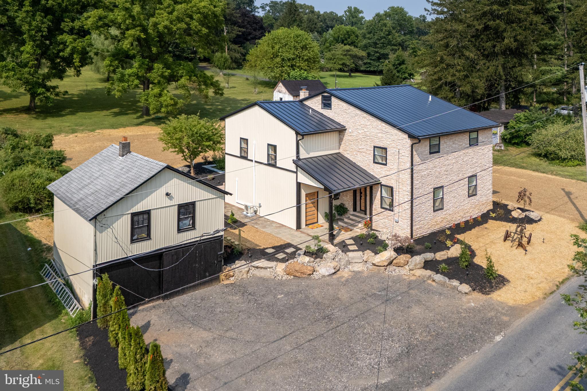 STUNNING FULLY RENOVATED MODERN FARMHOUSE on nearly 2 acres in Saucon Valley! This one-of-a-kind SMART HOME seamlessly blends rustic charm with modern luxury and features all new windows, HVAC system, a mini-split, electric, plumbing, LVP and tile flooring, and a to-be-installed septic system. The DRAMATIC EXTERIOR combines stone, wood, Hardie Board, a galvanized steel roof and custom maple doors- & is complemented by professional landscaping w/boulders and a backyard Koi pond! Inside, enjoy an open-concept living/dining area w/exposed beams and stone, a large picture window, wood-burning stove & an under the stairs kids' play nook! The eat-in kitchen impresses w/an oversized island, Corian countertops, and open shelving. A 1/2 bath completes this floor. Upstairs, the roomy primary suite boasts a luxurious ensuite bathroom w/2-person glass shower, floating Quartz vanity and porcelain tile walls & floor. There are 2 more bedrooms, a convenient laundry & a lavish hall bath w/a soaking tub, glass shower & sliding barn door. A private GUEST/IN-LAW SUITE includes a 4th BR w/a large picture window, 2nd kitchen w/SS appliances, 3rd full BA & a bright LR w/another large picture window overlooking the backyard. Entertain or relax on the MAGNIFICENT BACK PORCH, while enjoying the soothing sounds of the pond fountain, views of the sunset and pure serenity of this property. The detached 2-car garage w/loft allows for added storage, an office or artist studio! Within minutes to the Steel Club, Saucon Valley CC, Rails to Trails and restaurants/shops!