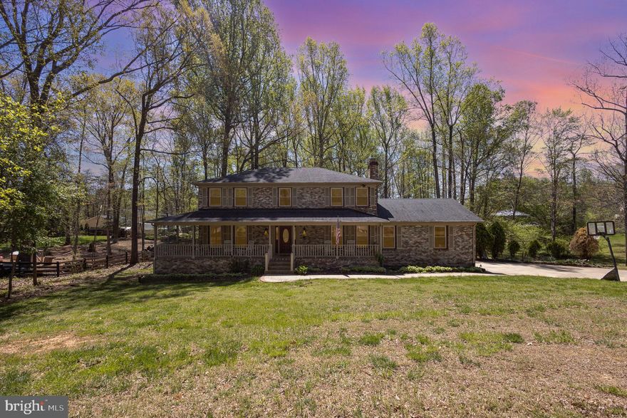 Tucked away on a beautifully landscaped, tree-lined acre, this stunning 3-level brick-front home is the one you've been waiting for. From the moment you arrive, the wrap-around front porch, stamped concrete walkway, and landscaping set the tone for something special.  Inside, you'll find a blend of classic elegance and cozy comfort – from the formal living and dining rooms – to the spacious kitchen and inviting family room featuring wood-beamed ceilings and a gas fireplace. At the rear of the home, a light-filled sunroom offers serene views of the private backyard—an ideal space to unwind. Upstairs, the generous primary suite boasts walk-in closets and an en-suite bath. Three additional bedrooms and a full hall bath offer plenty of room for family or guests. The fully finished walkout basement expands your living space with a large rec room, fifth bedroom, full bath, and ample storage. Outside, the two-tiered deck offers the perfect space for summer gatherings and enjoying nature. Centrally located between Mountainview Road and Rt. 610, this gem offers easy access to top-rated schools, shopping, dining, and a quick commute to Quantico and Northern Virginia.